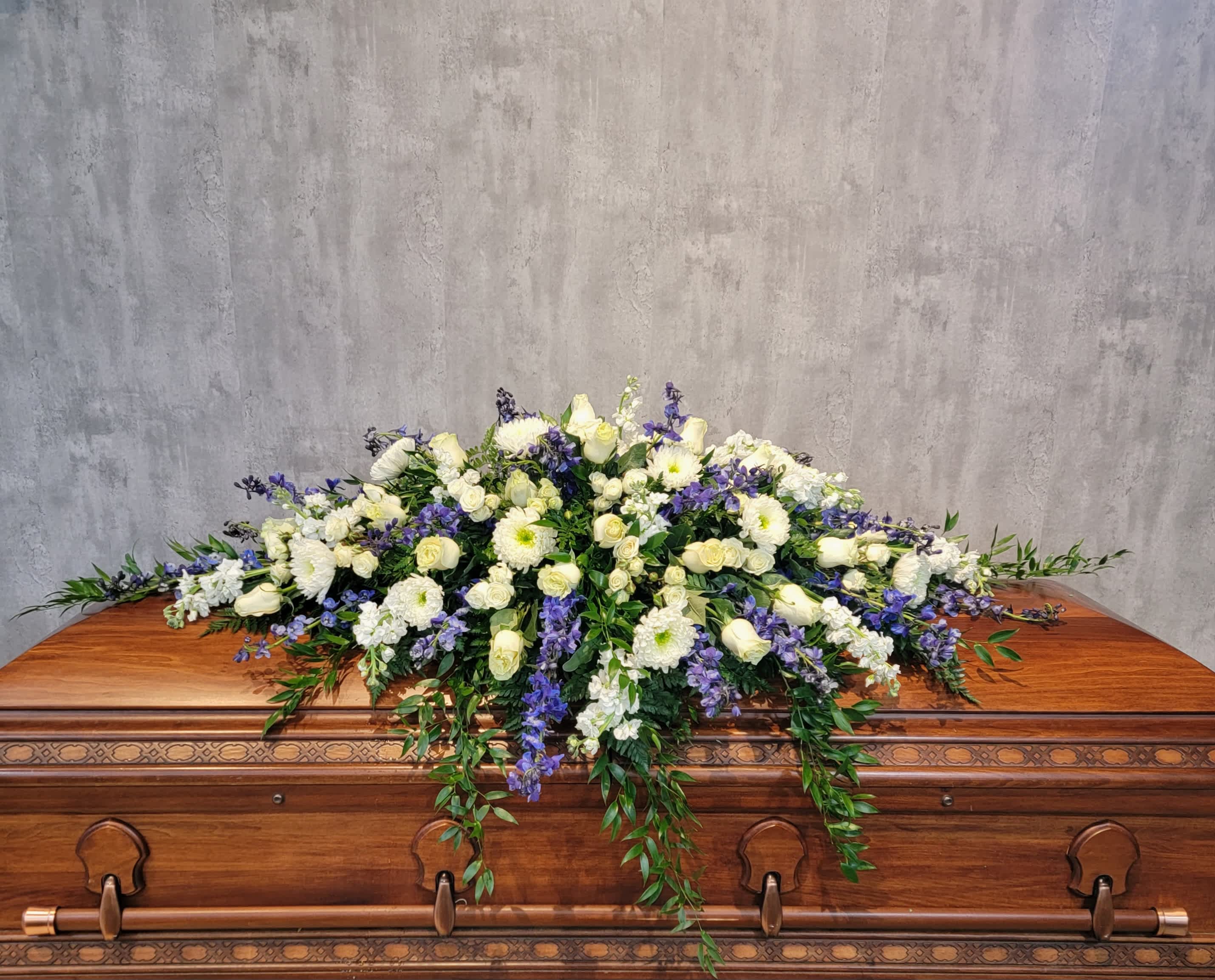 White and purple floral spray on a wooden casket