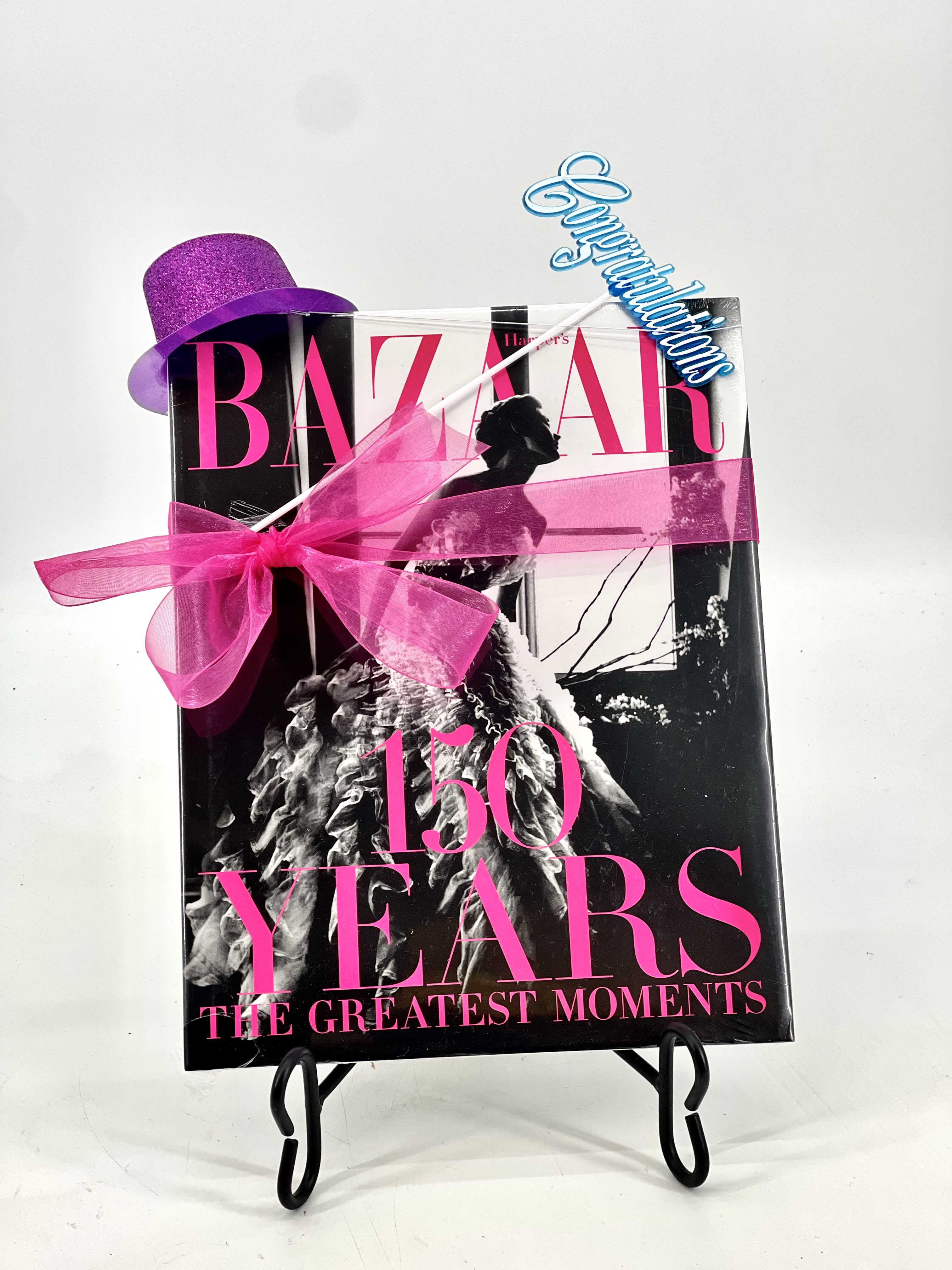 Gift-wrapped Harper's Bazaar 150 Years book with a purple hat and pink ribbon