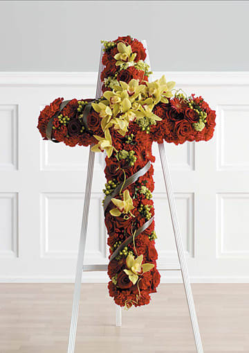 Standing cross-shaped spray of red flowers with yellow orchids on a white easel