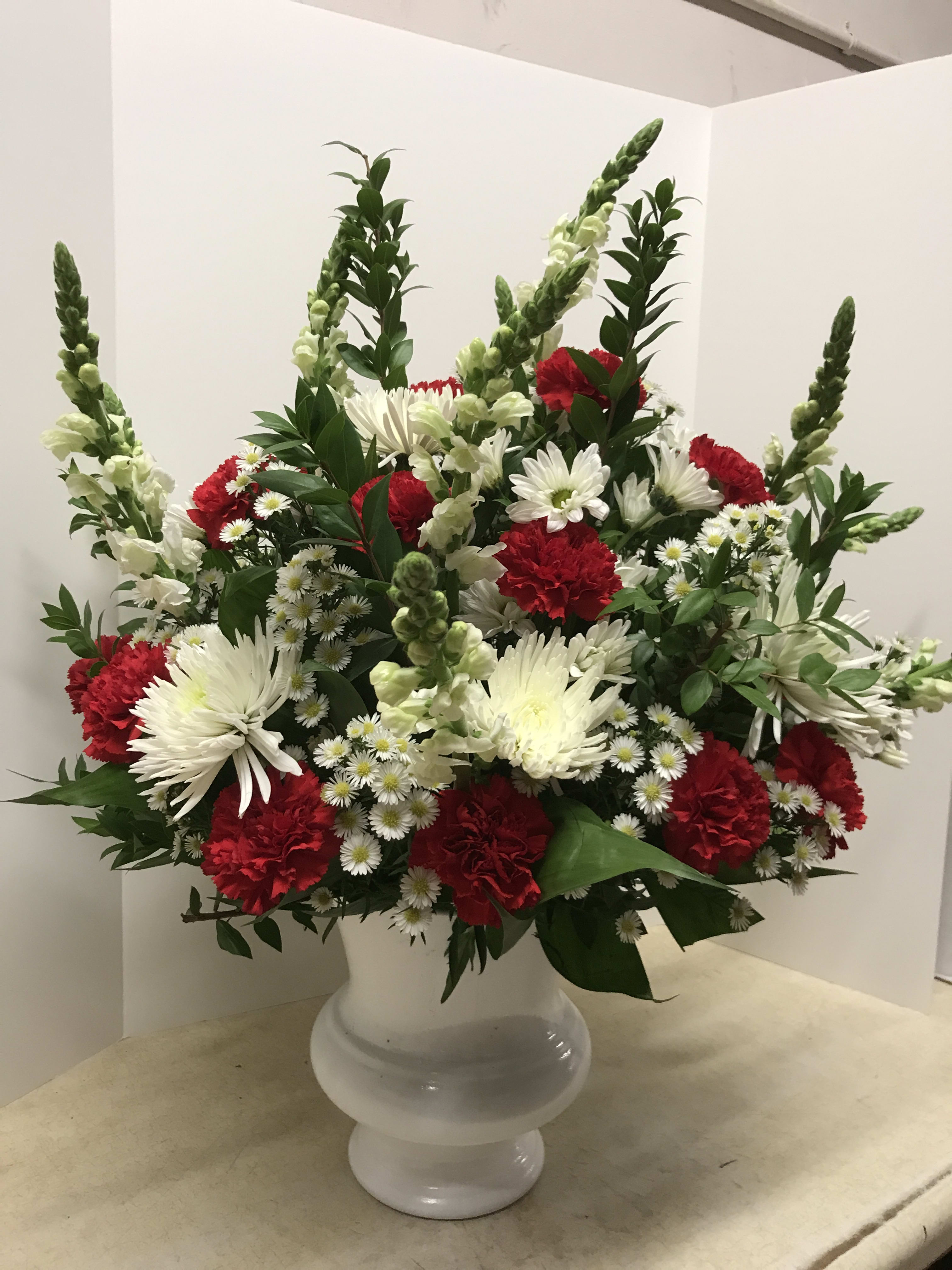Red and white floral arrangement in a white vase