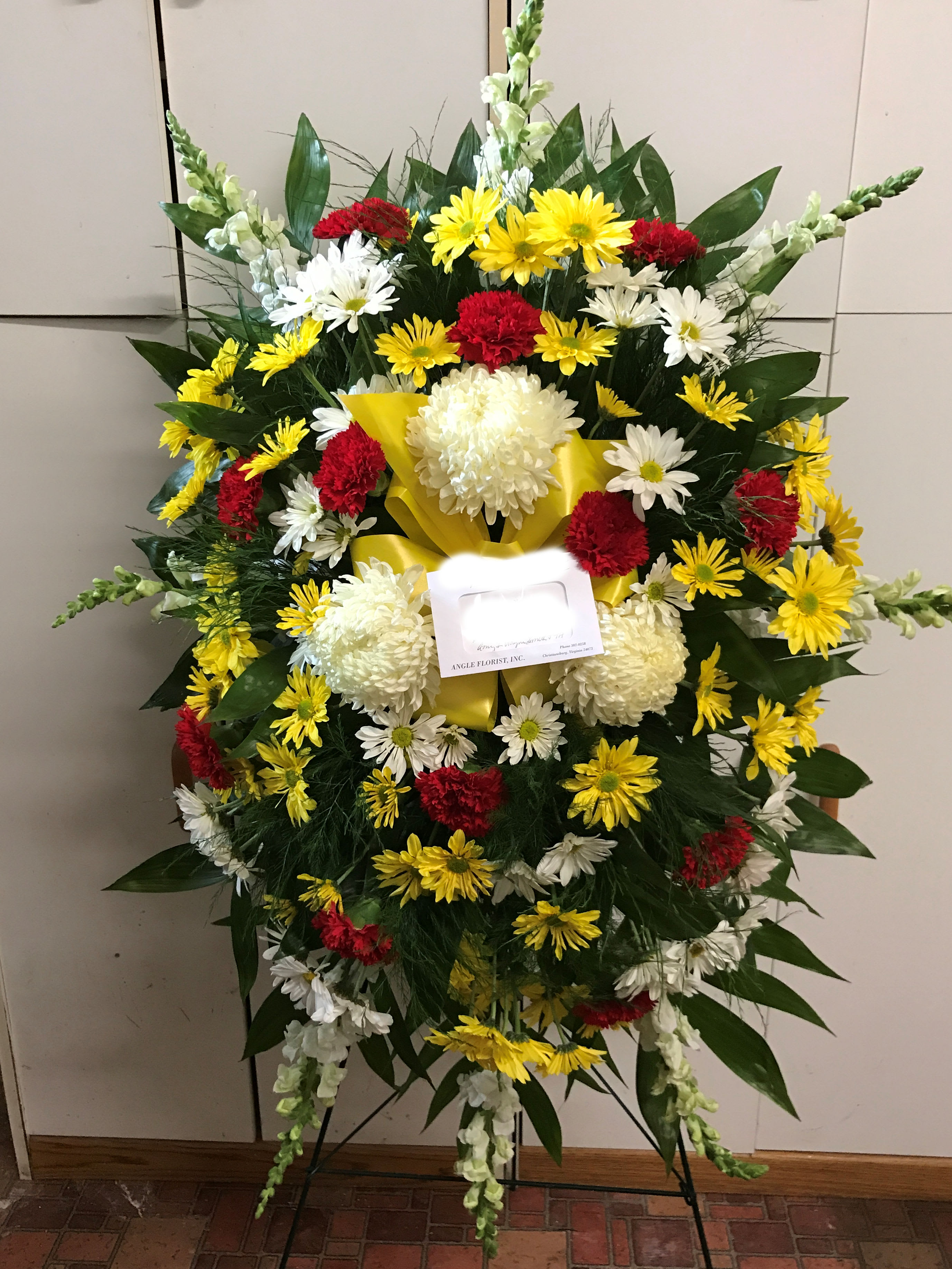 Standing Funeral Spray - Our basic standing funeral spray begins at $150.00 and consists of various colors of flowers designed on an oasis block with greenery.  As the price increases to $175.00, we design the standing spray in an oasis block soaked in water, and add a variety of flowers to the spray appropriate for the price range.  As with any design, additional flowers are added that provide the nicest show for the money spent.  Such things as snapdragons, daisies, roses, spider mums, pom pons, etc. can be added in order to meet the specified price range.  If you desire a specific flower or design, please feel free to call the shop directly and discuss your selection with us.  