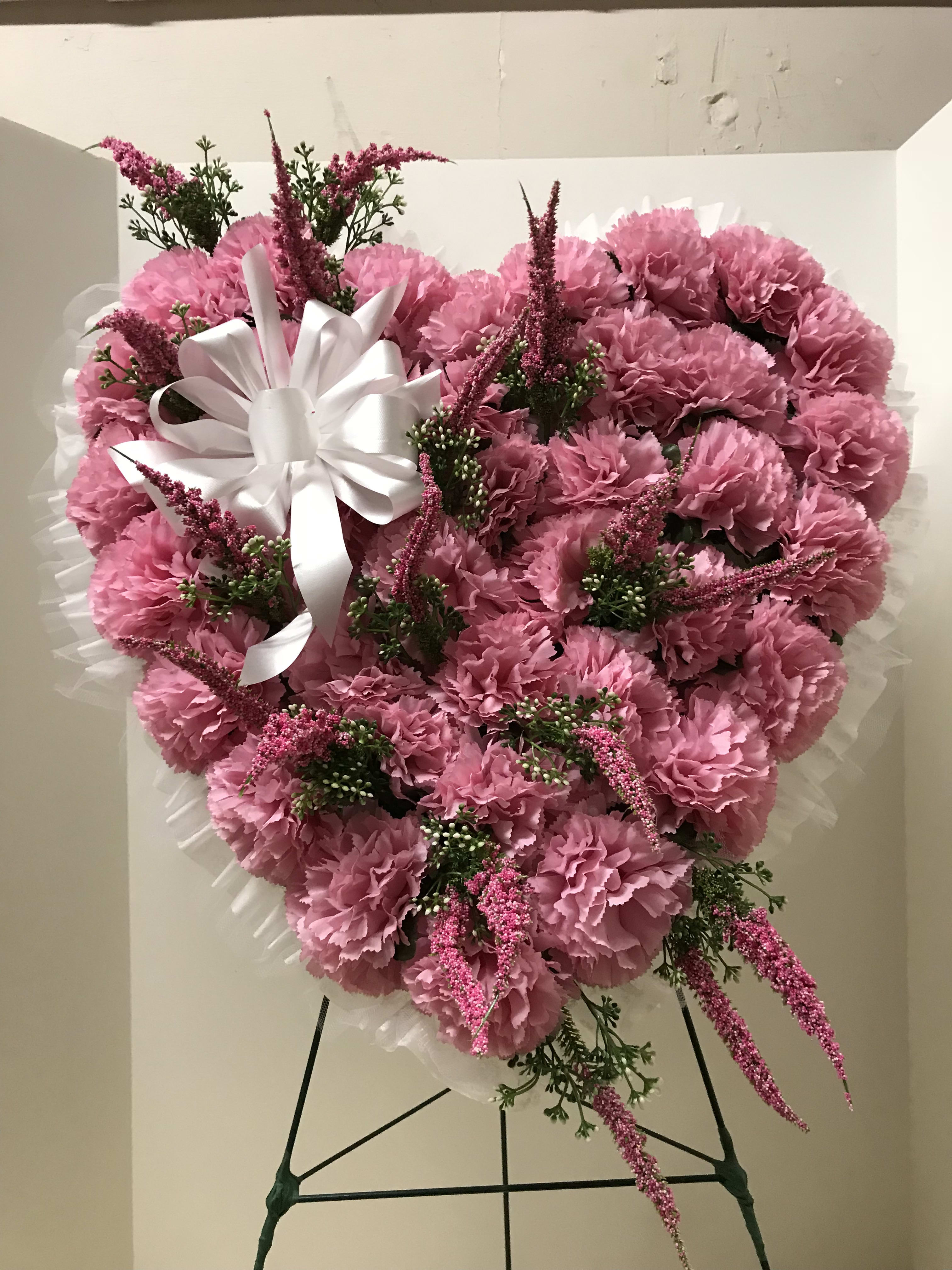 Heart-shaped pink carnation arrangement with a white ribbon bow