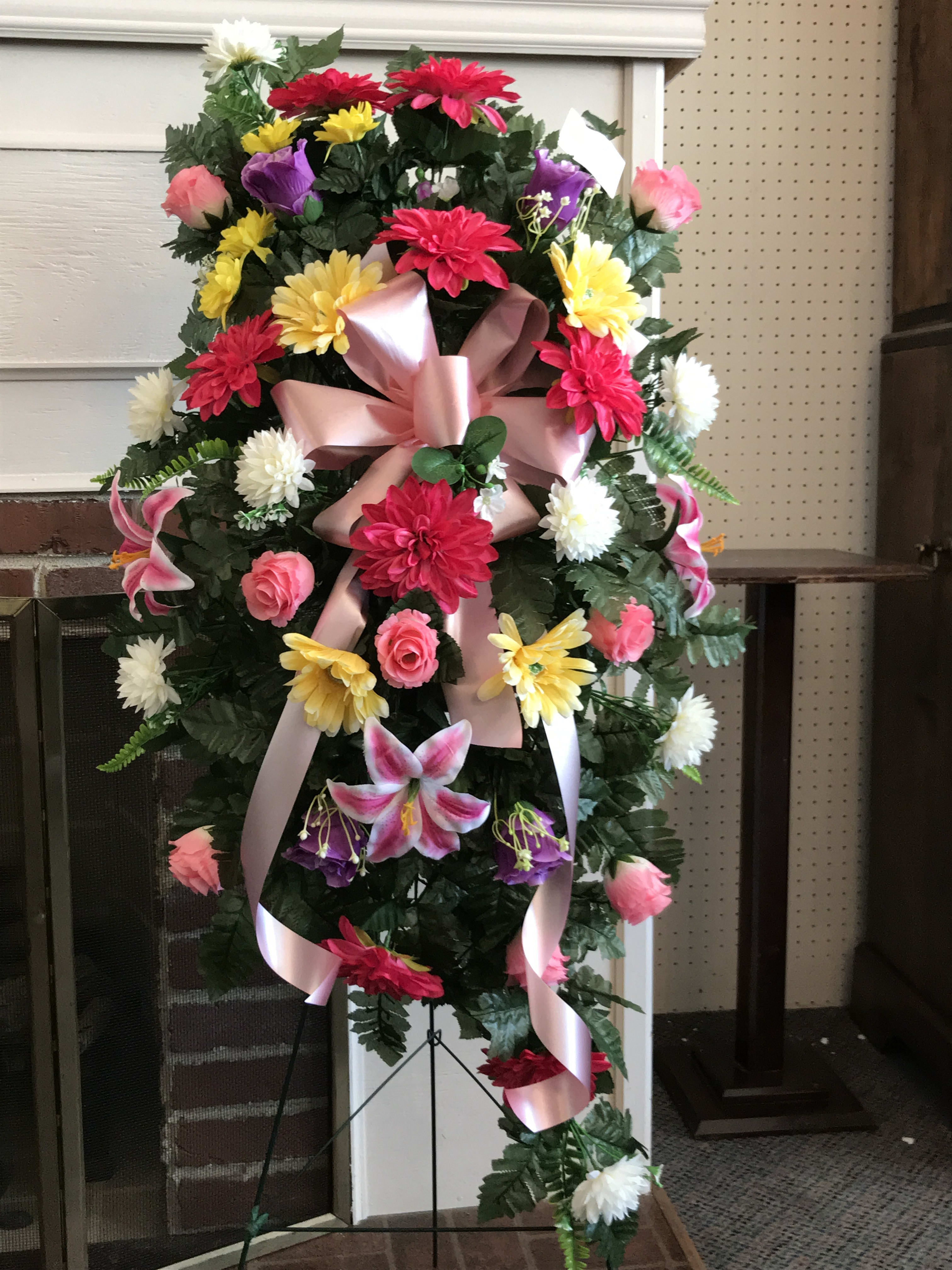 Standing floral spray with pink ribbon and mixed bright flowers