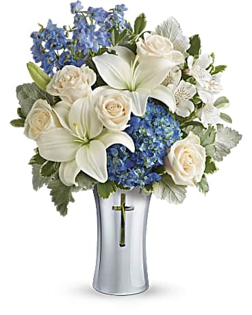 Skies of Remembrance Bouquet - An elegant expression of your deepest condolences, this majestic mix of blue hydrangea and white lilies will refresh and rejuvenate their spirits. It's hand-delivered in a shining, silver-finished ceramic vase with cross cut-out - a serene, spiritual keepsake they'll always treasure.  This majestic bouquet includes blue hydrangea, white asiatic lilies, white alstroemeria, light blue delphinium, dusty miller and variegated pittosporum.  Delivered in a Shining Silver Cross vase.  Orientation: All-Around  SUBSTITUTION POLICY – Always deliver the freshest flowers! Please note the bouquet pictured reflects an original design.  If the exact flowers or container in this arrangement are not available, we will create a beautiful bouquet with the freshest available flowers.