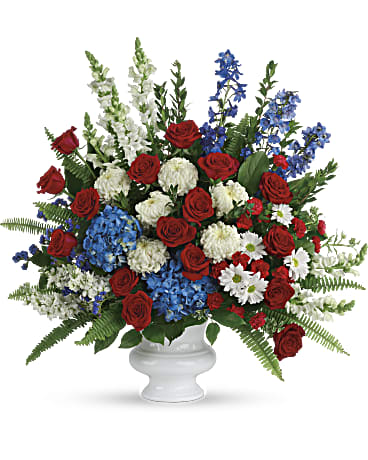 Red roses, white flowers, and blue blooms in a white vase