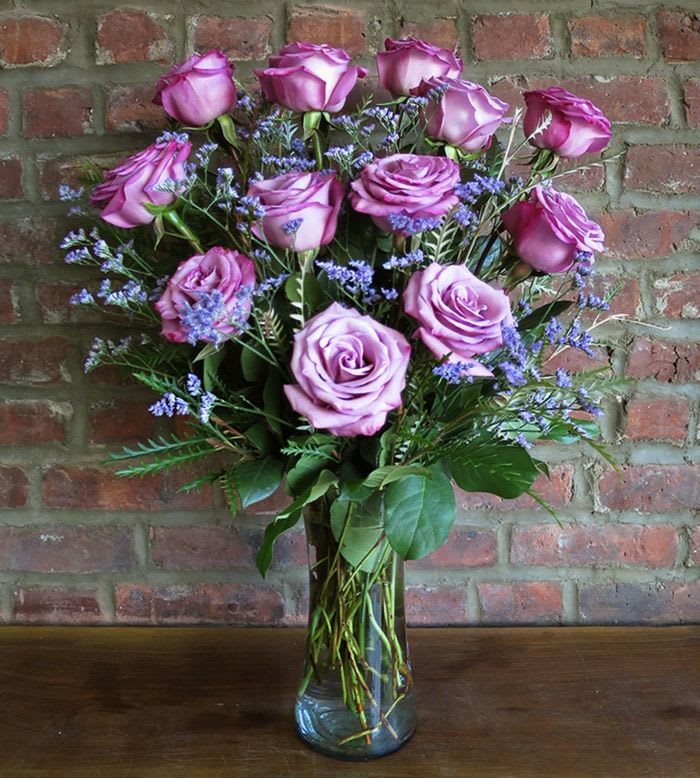 Bouquet of lavender roses with purple filler in a glass vase