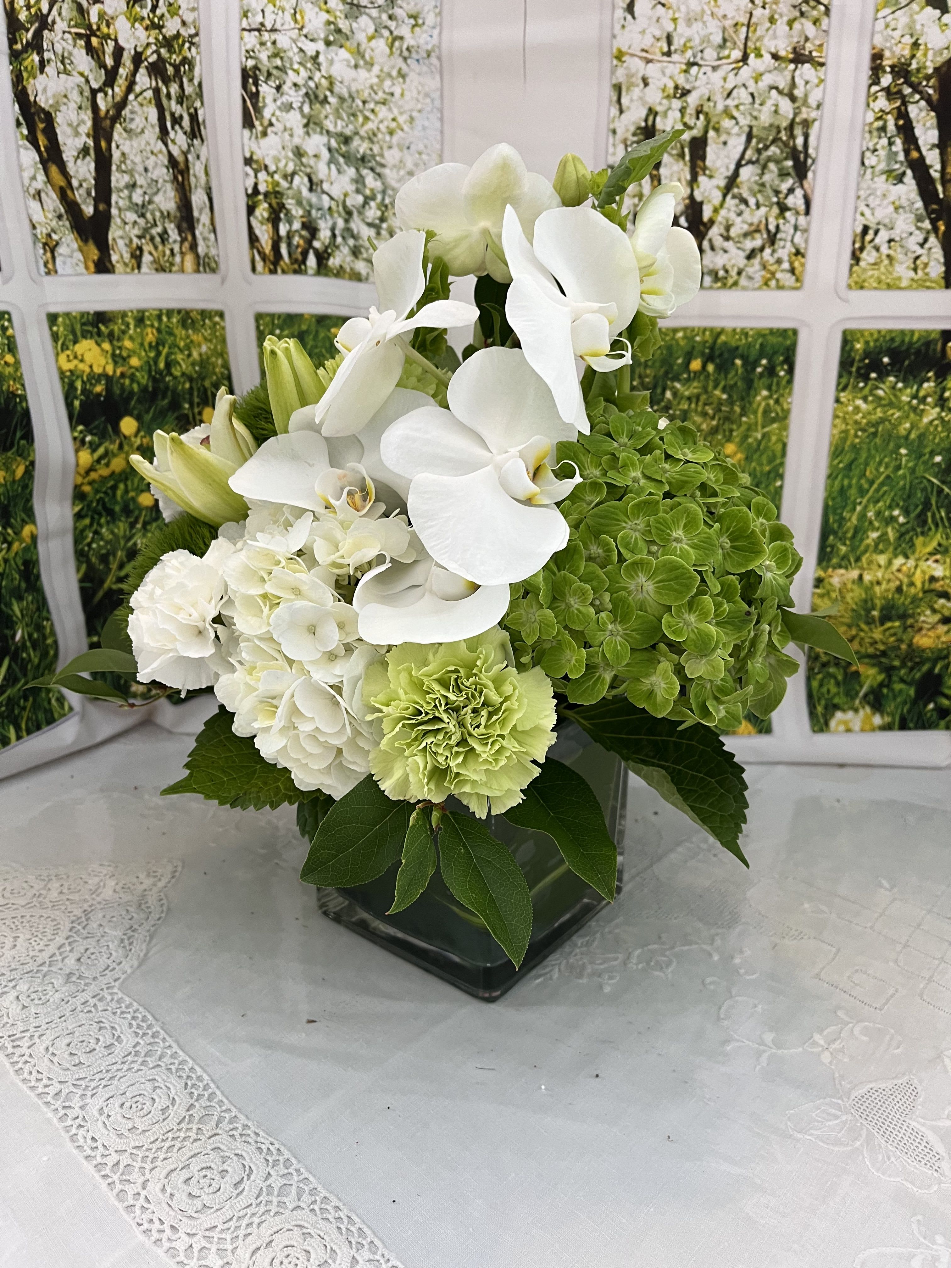 White orchids and green hydrangeas in a square glass vase