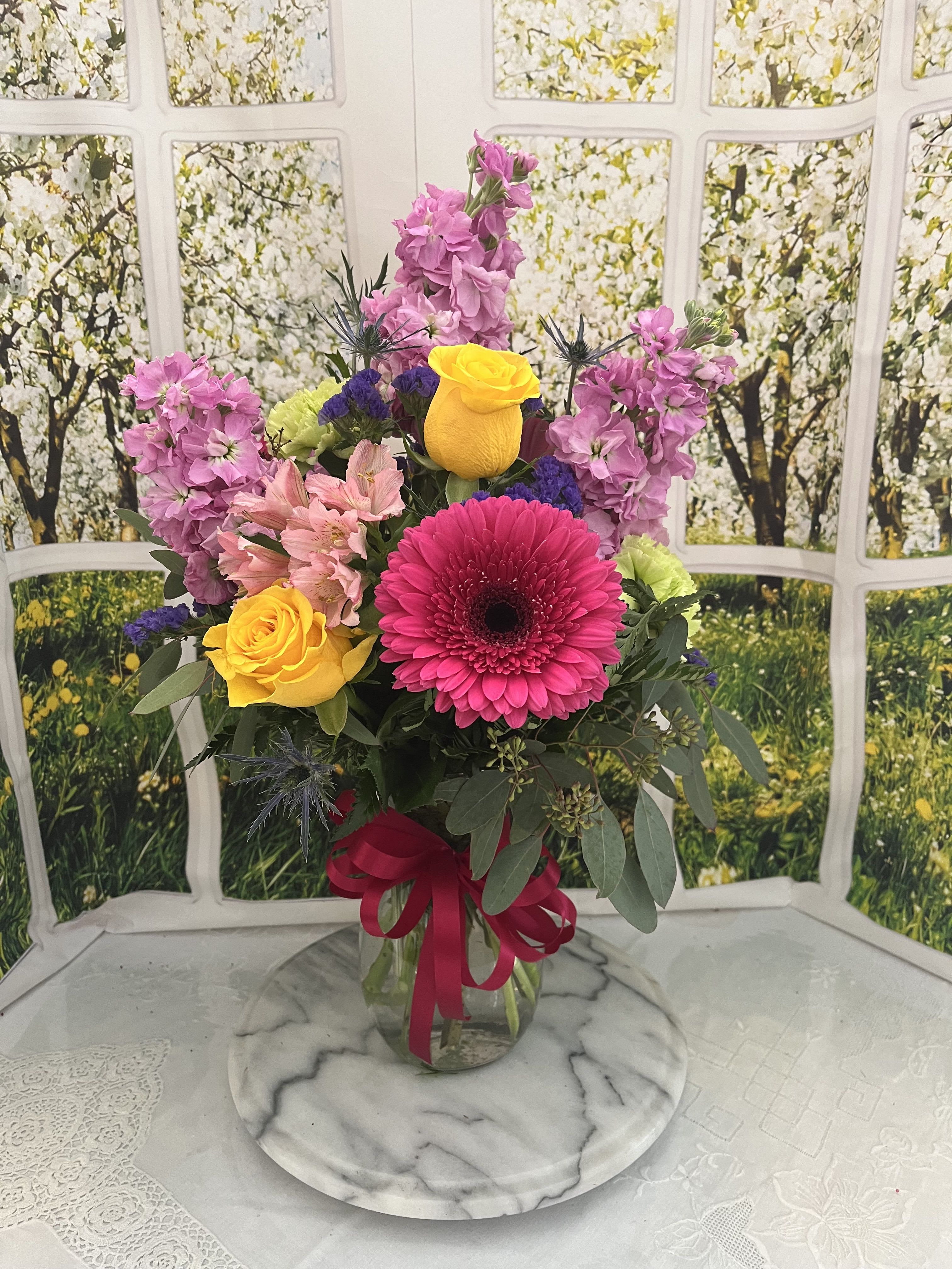 Mixed bouquet in a glass vase with pink, yellow, and purple flowers