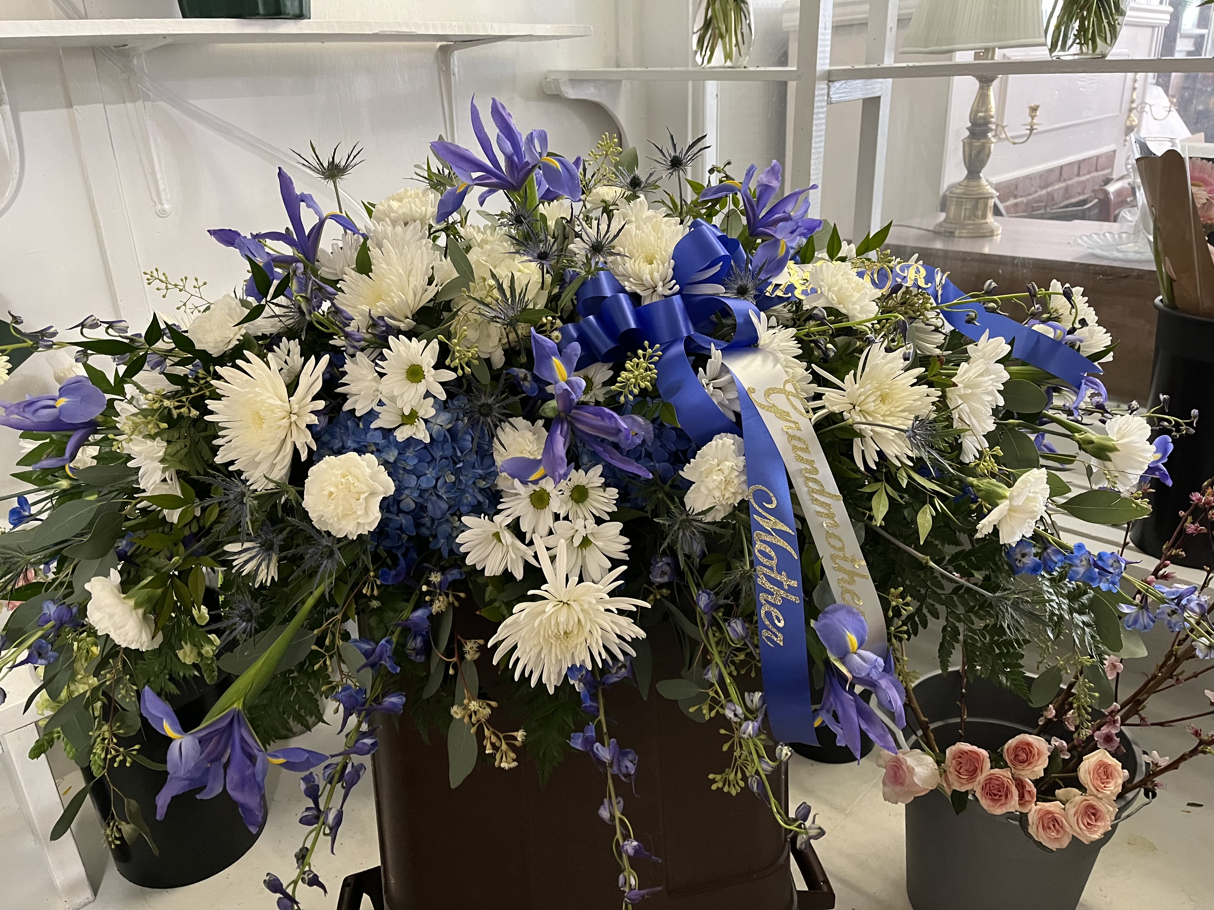 Large blue and white floral spray with ribbon in a container