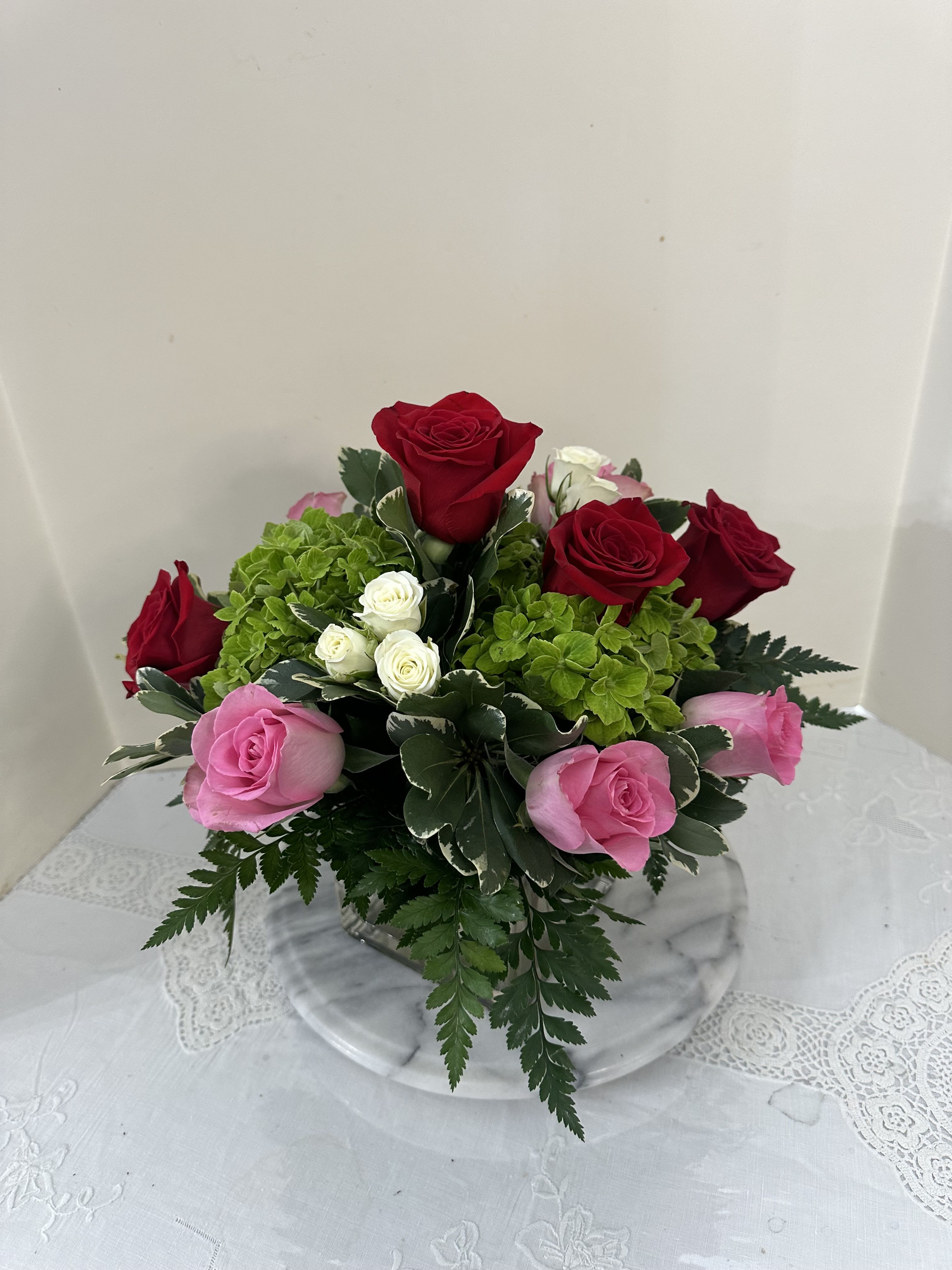 Bouquet of red and pink roses with green hydrangea in a glass vase