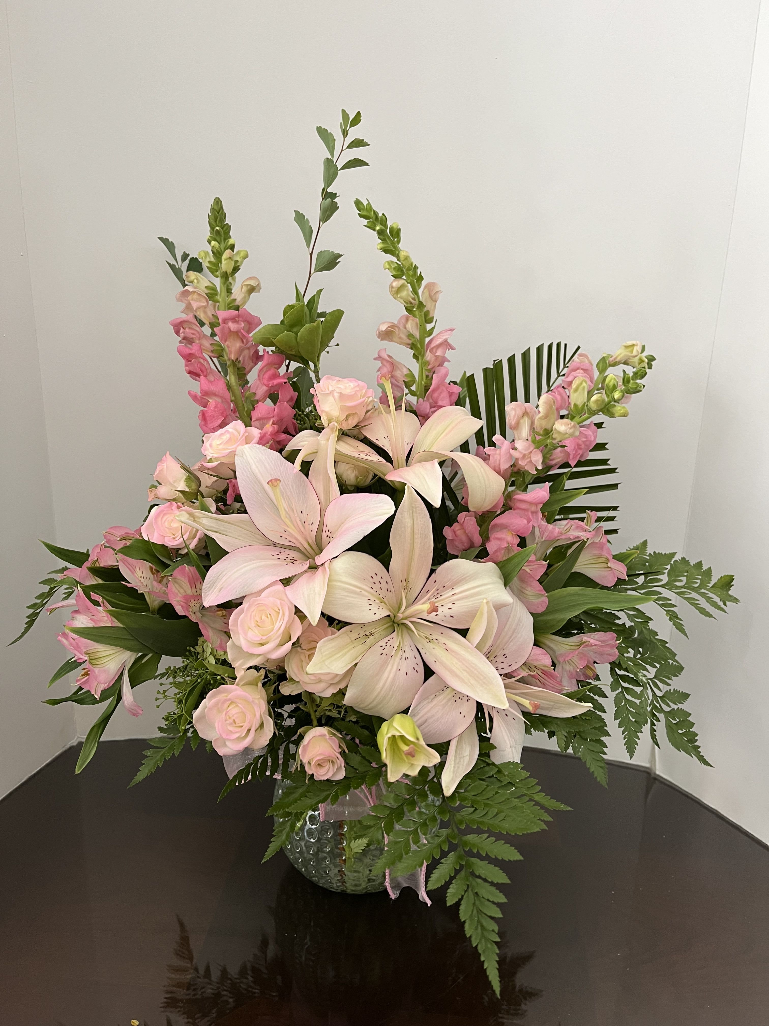 Pink lilies and roses arranged in a glass vase
