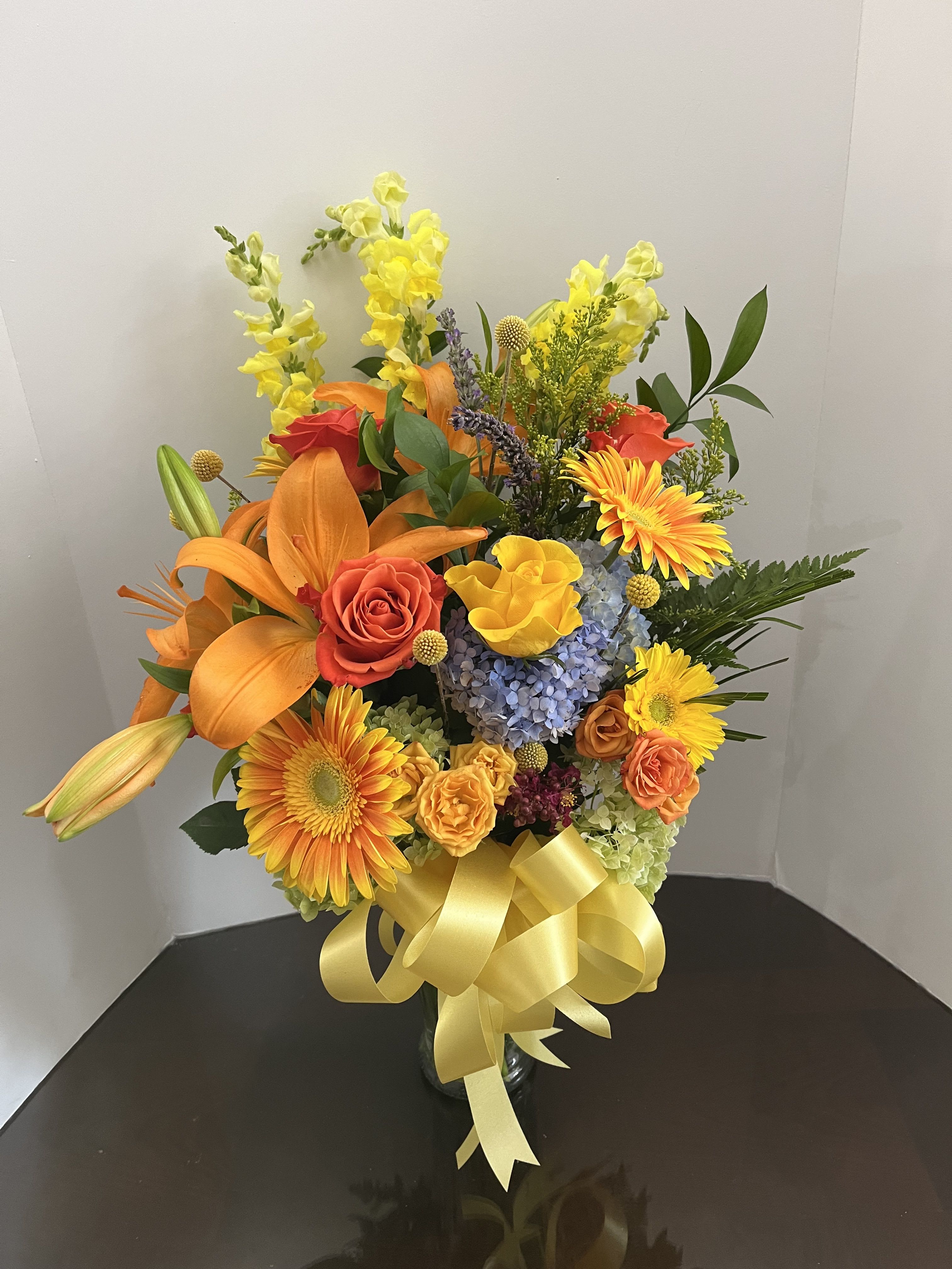 Sunshine Smiles - This is a bright bouquet sure to leave a smile on someone's face! Complete with lovely Gerbera daisies, roses, hydrangeas, lilies, and snapdragons. 
