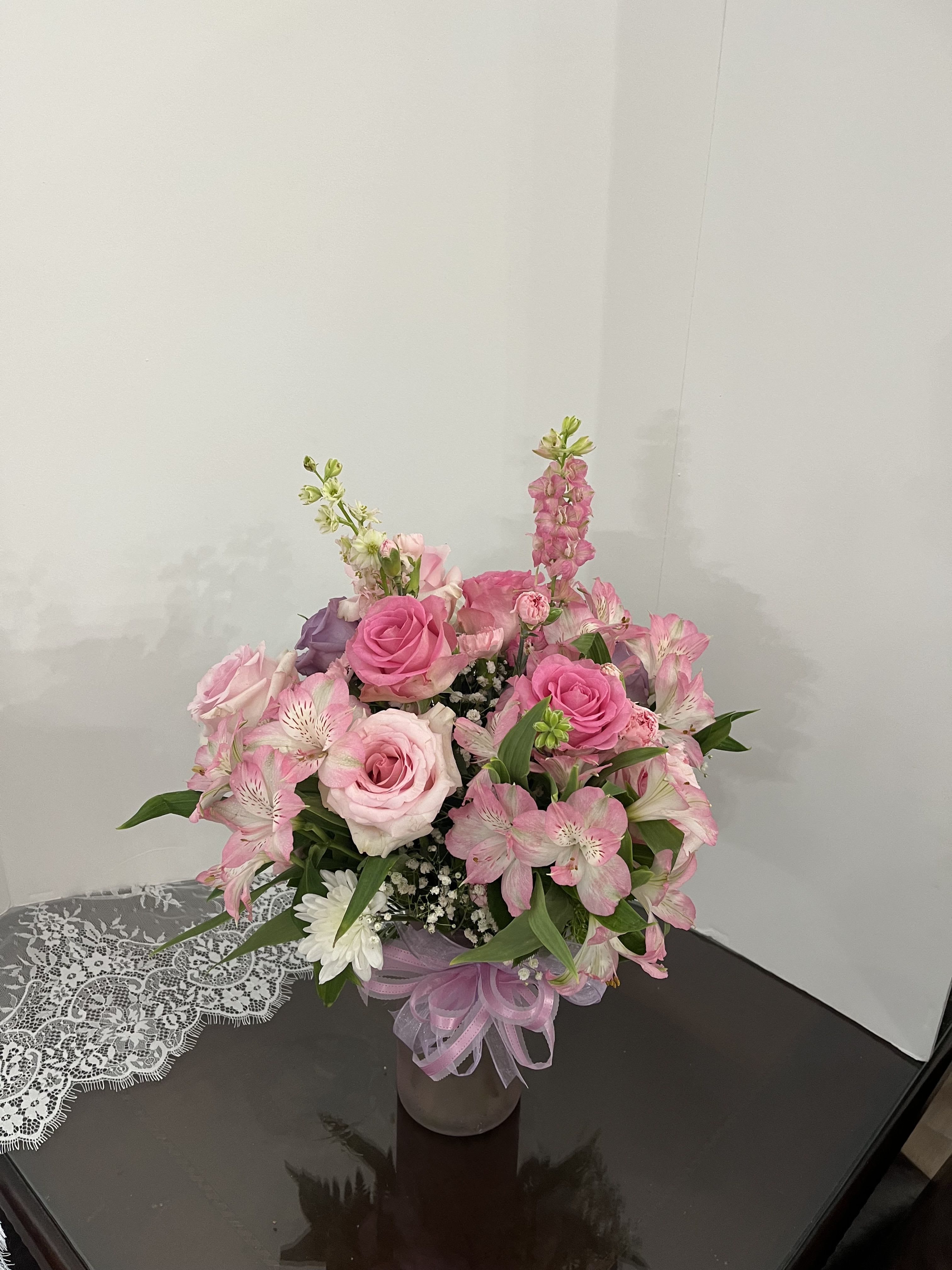 Pink rose bouquet with alstroemeria in a glass vase tied with ribbon