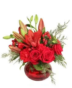 Red roses and lilies arranged in a red glass vase