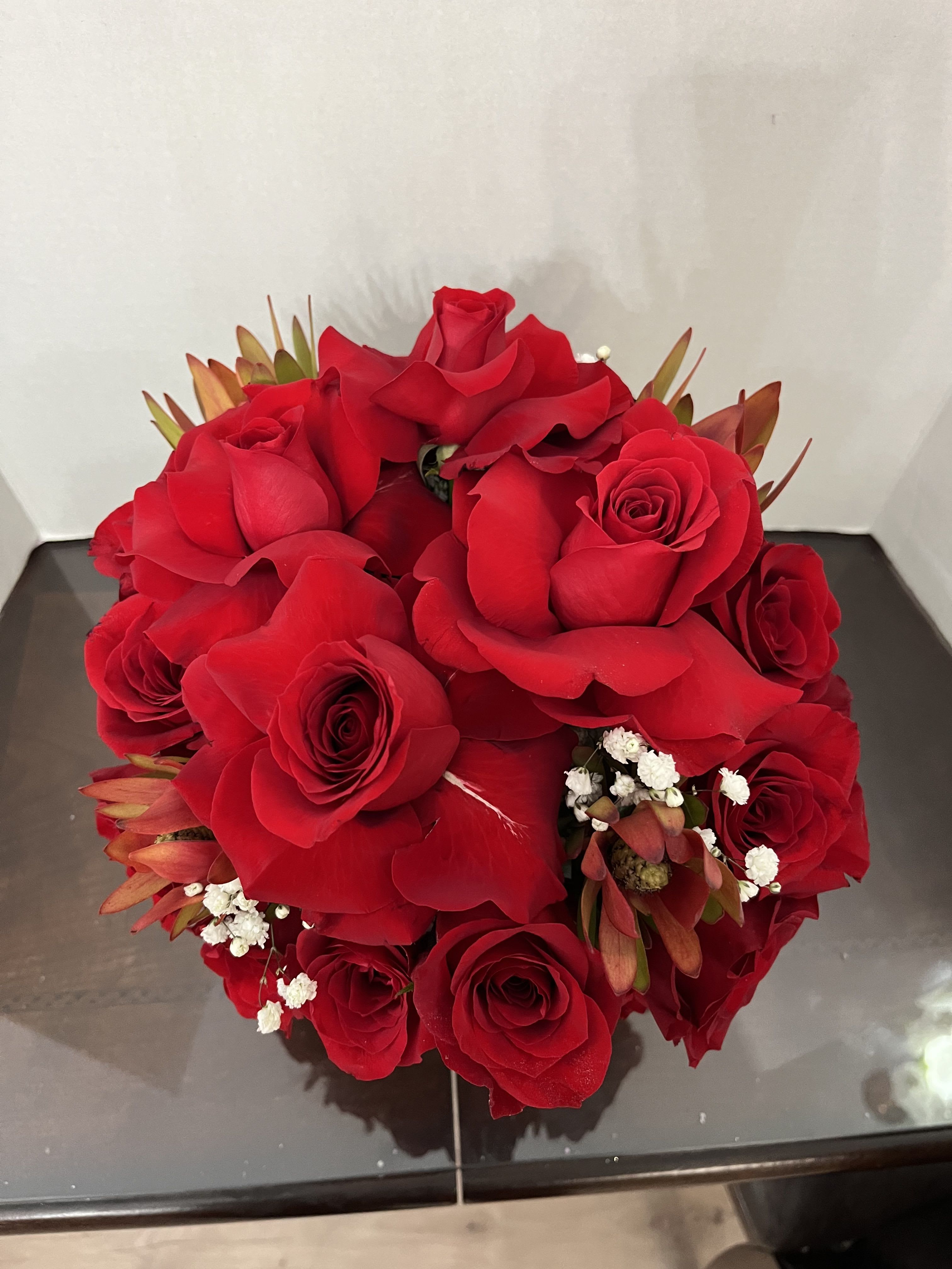 Round bouquet of red roses with small white filler flowers