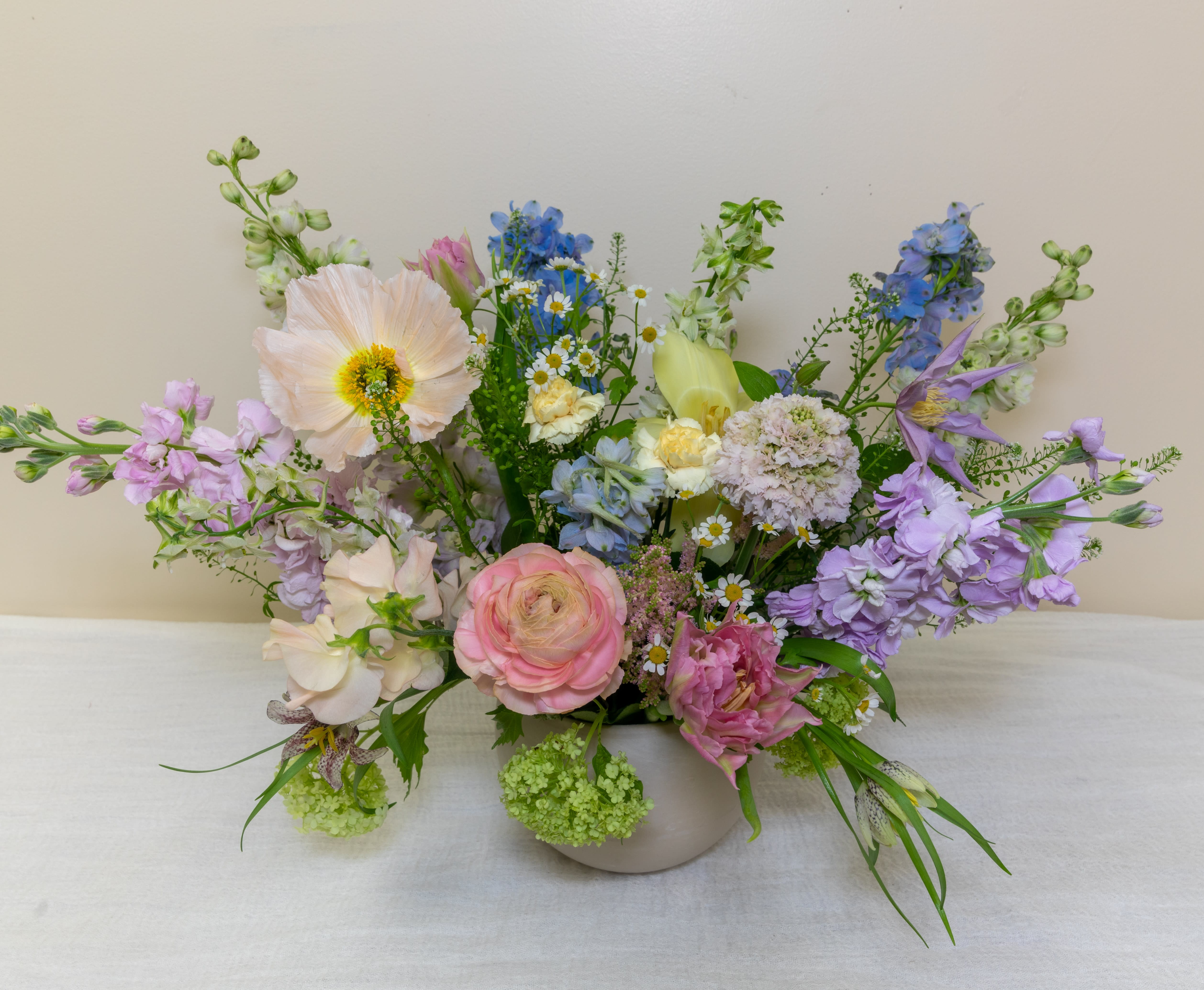 Pastel mixed flower arrangement in a low white vase