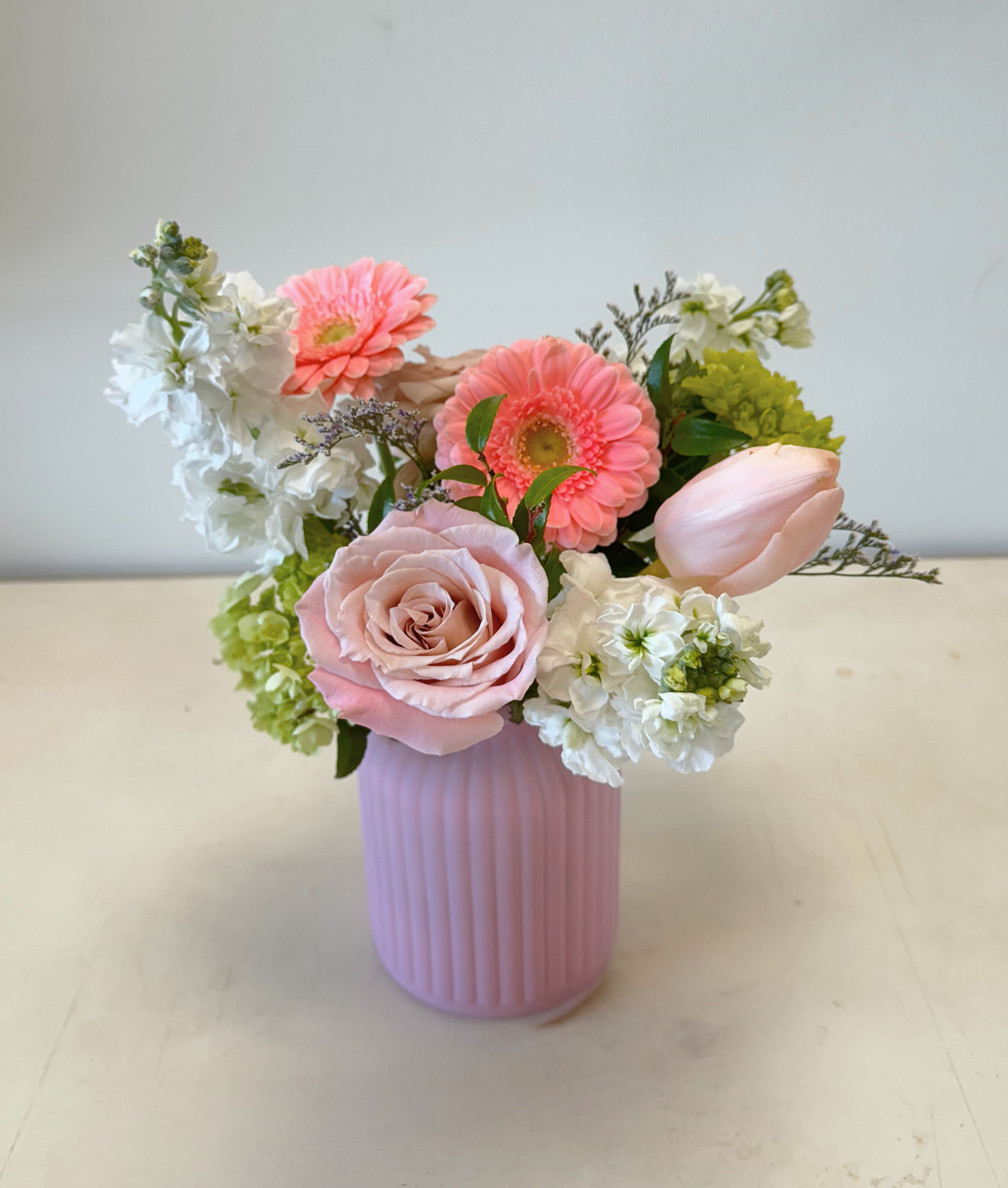 Pink and white flower arrangement in a ribbed pink vase