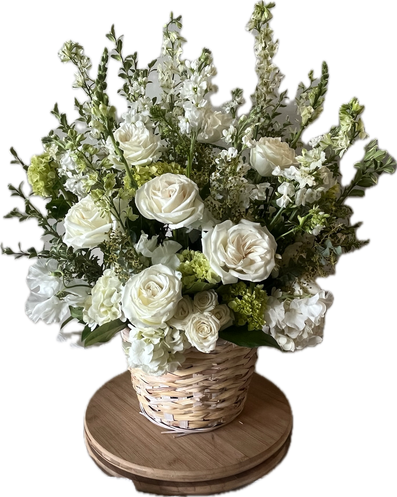 Pure Remembrance Garden Style Basket - Pure Remembrance is a timeless and elegant floral tribute of all-white blooms, symbolizing peace and enduring love. This basket is designed with more of a garden feel, with more green and texture than the traditional Pure Remembrance Basket. The basket is upright and designed to be taller than wide to offer soft strength with timeless beauty. This piece may include elegant white roses and lush hydrangea, with white snapdragons, stock, and delphinium, or our freshest available arrangement of all white blooms with accents of green and texture.  This arrangement is thoughtfully designed using the freshest flowers available for the season. While the overall look and palette will be honored, specific flowers may vary. Advance notice is requested for funeral arrangements due to the scale of these designs.