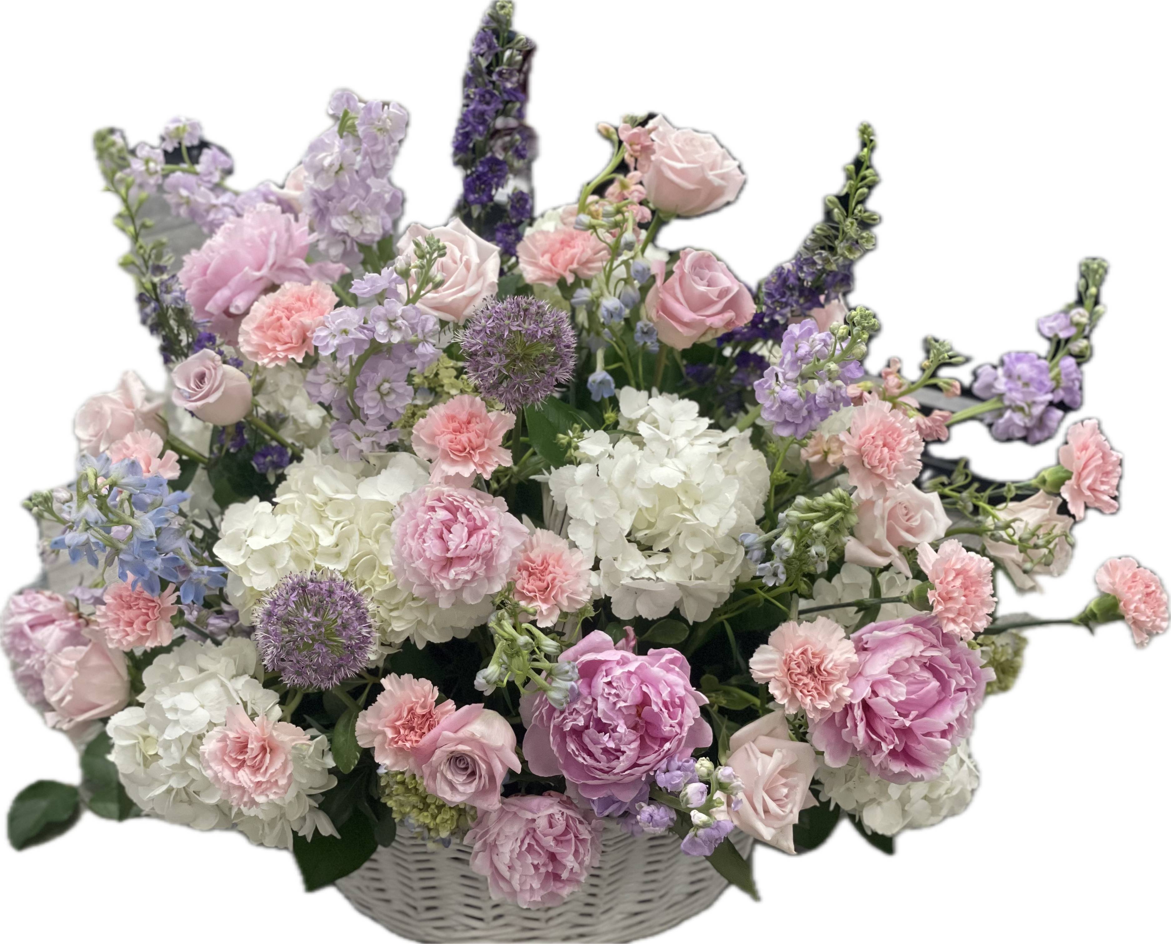 Soft Serenity Basket - Soft Serenity is a peaceful tribute, offering a calming presence through soft purple and pink tones with gentle accents of white. This collection symbolizes grace and the quiet beauty of a life well lived. Featuring white and mini green hydrangeas, soft pink and purple roses, lavender stock and snapdragons, featuring seasonal light pink Spring peonies. This arrangement is thoughtfully designed using the freshest flowers available for the season. While the overall look and palette will be honored, specific flowers may vary. Advance notice is requested for funeral arrangements due to the scale of these designs. 