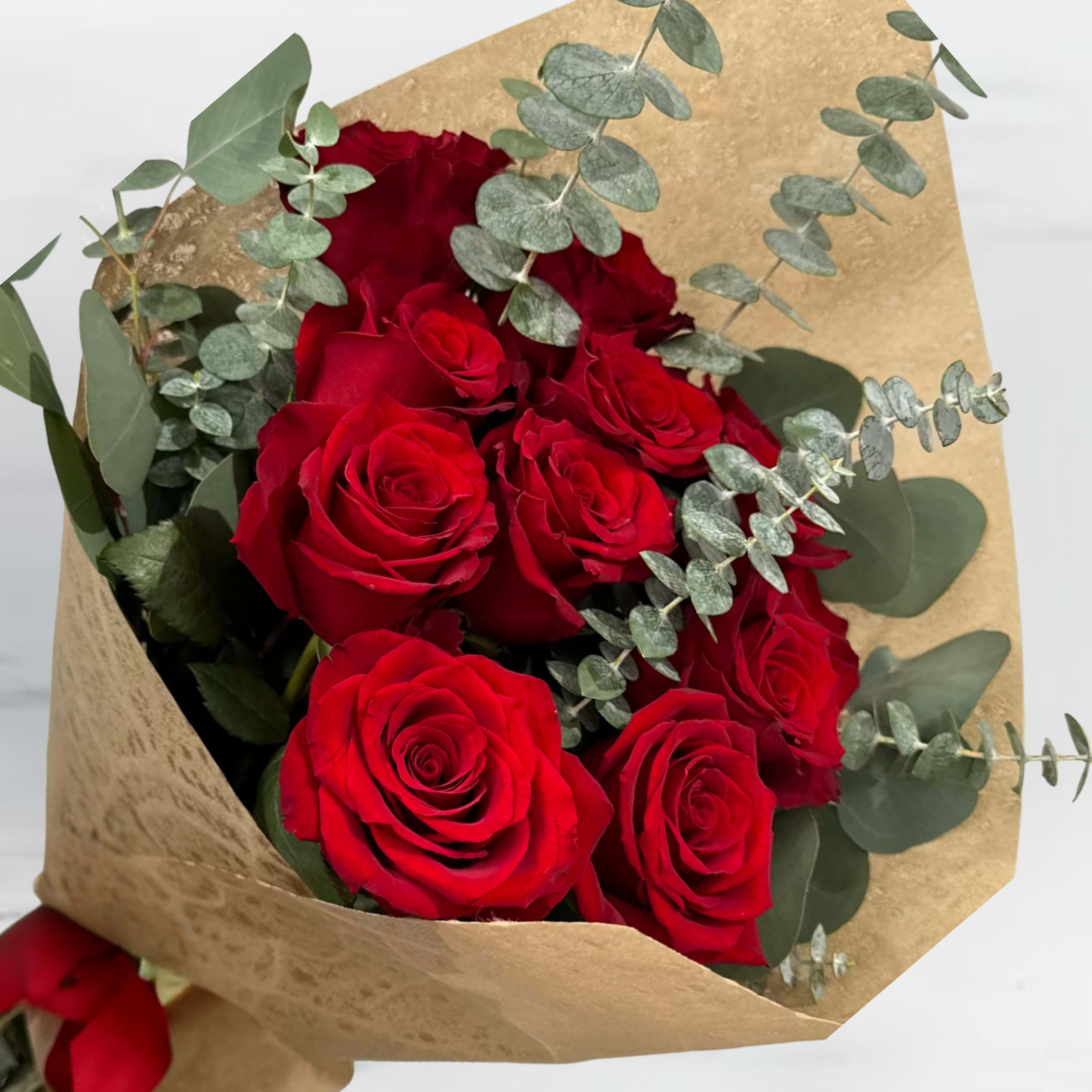 Bouquet of red roses wrapped in gold paper with eucalyptus