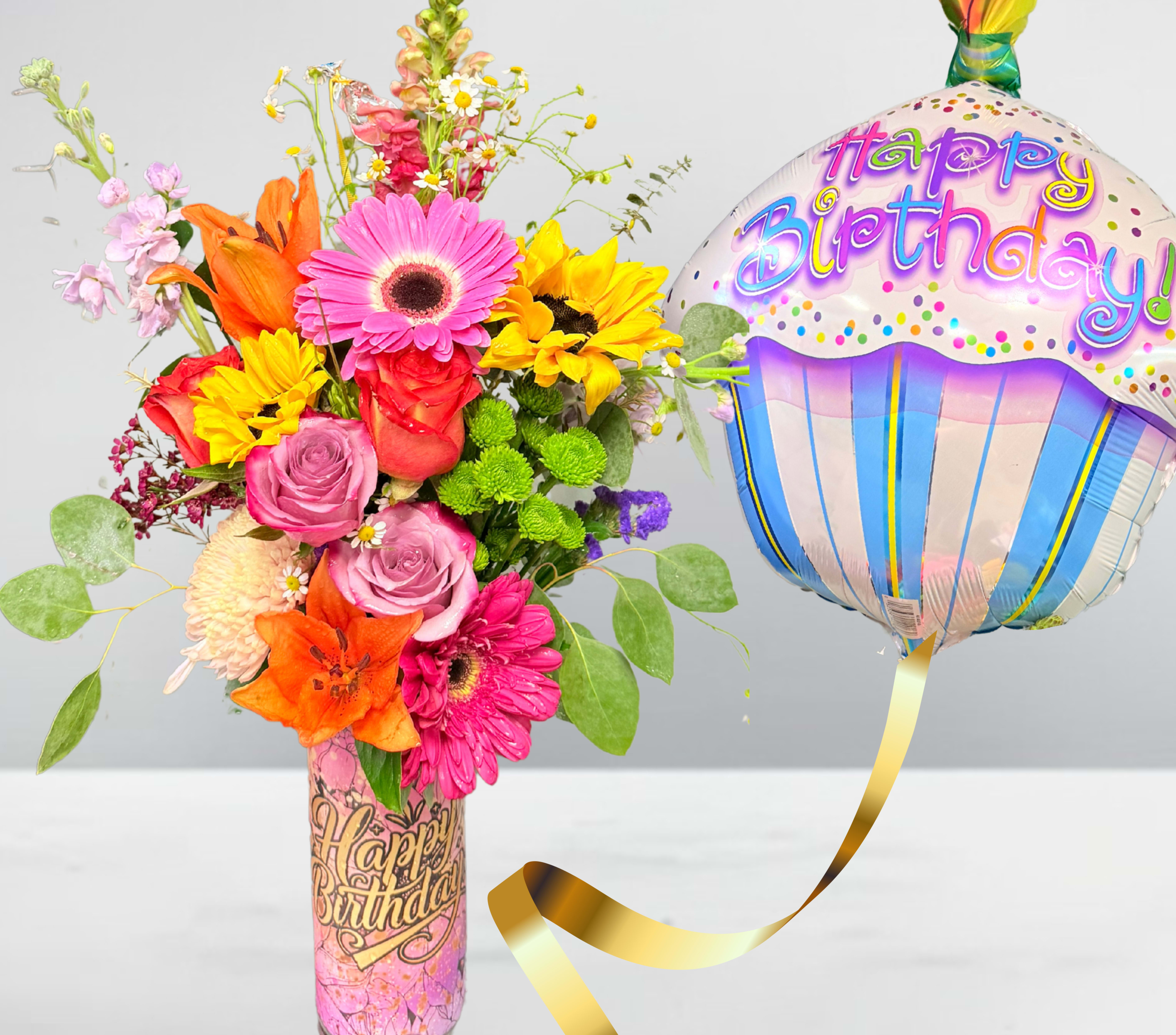 Colorful mixed flower bouquet with a birthday balloon in a decorated vase