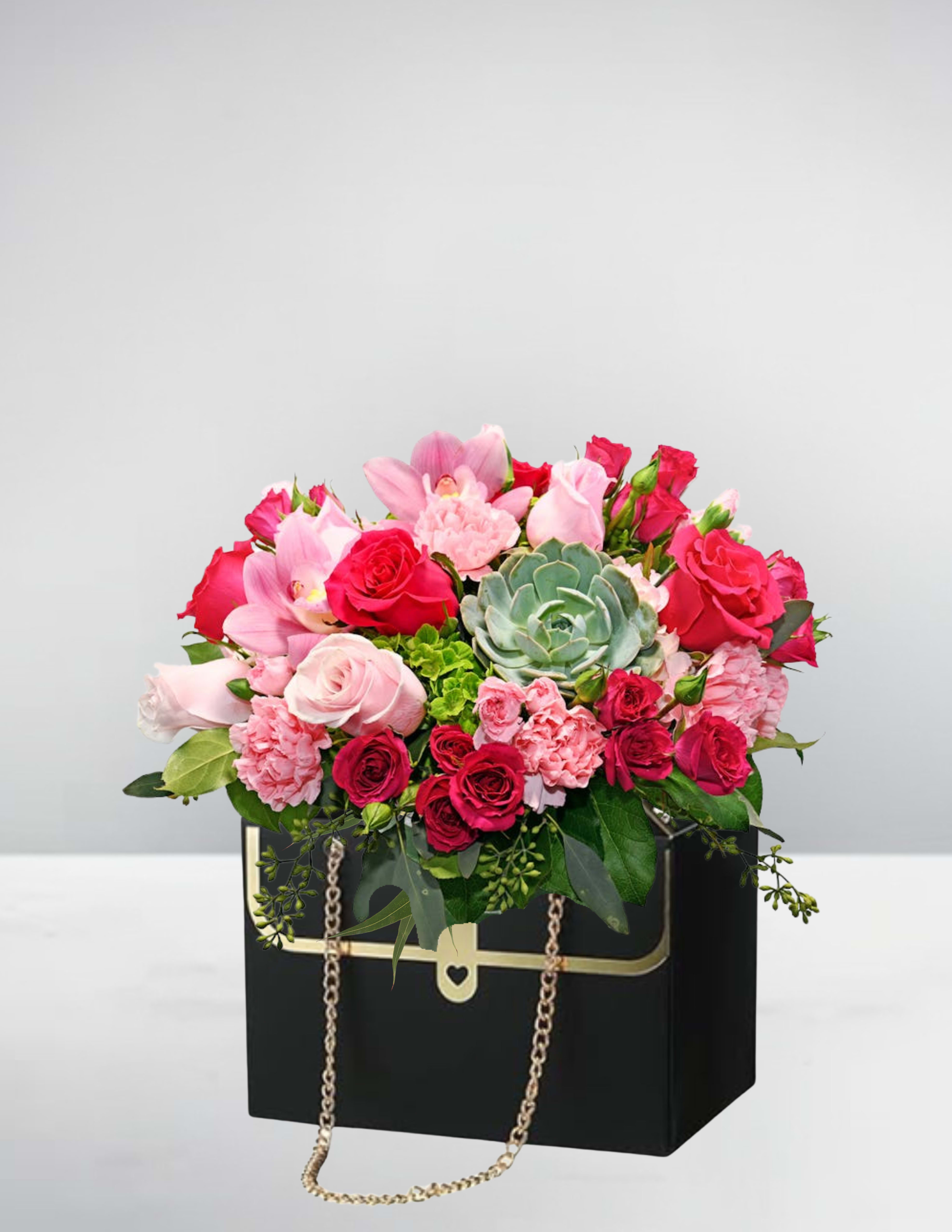 Pink and red rose bouquet in a black box with a gold chain handle