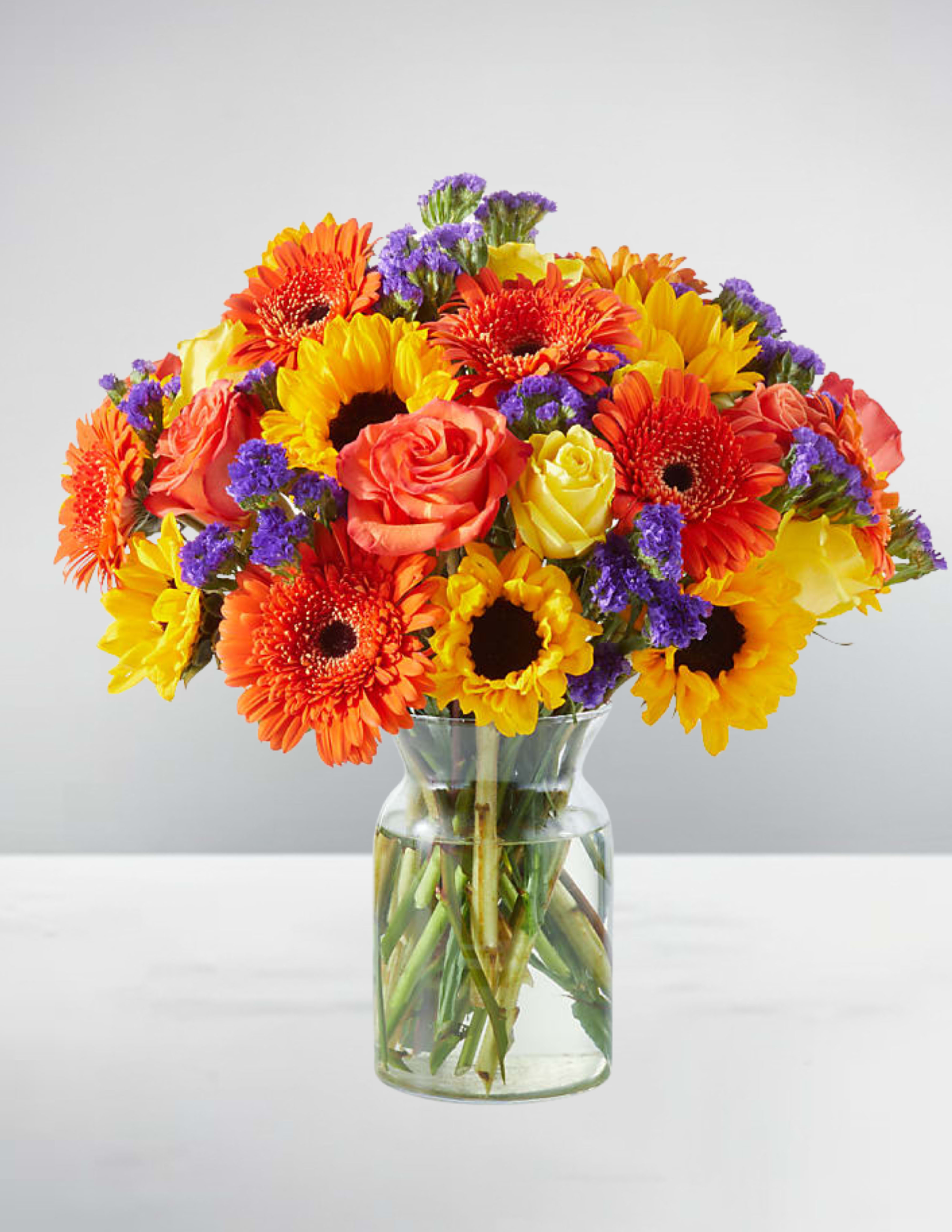 Bright mixed bouquet of gerbera daisies and roses in a glass vase