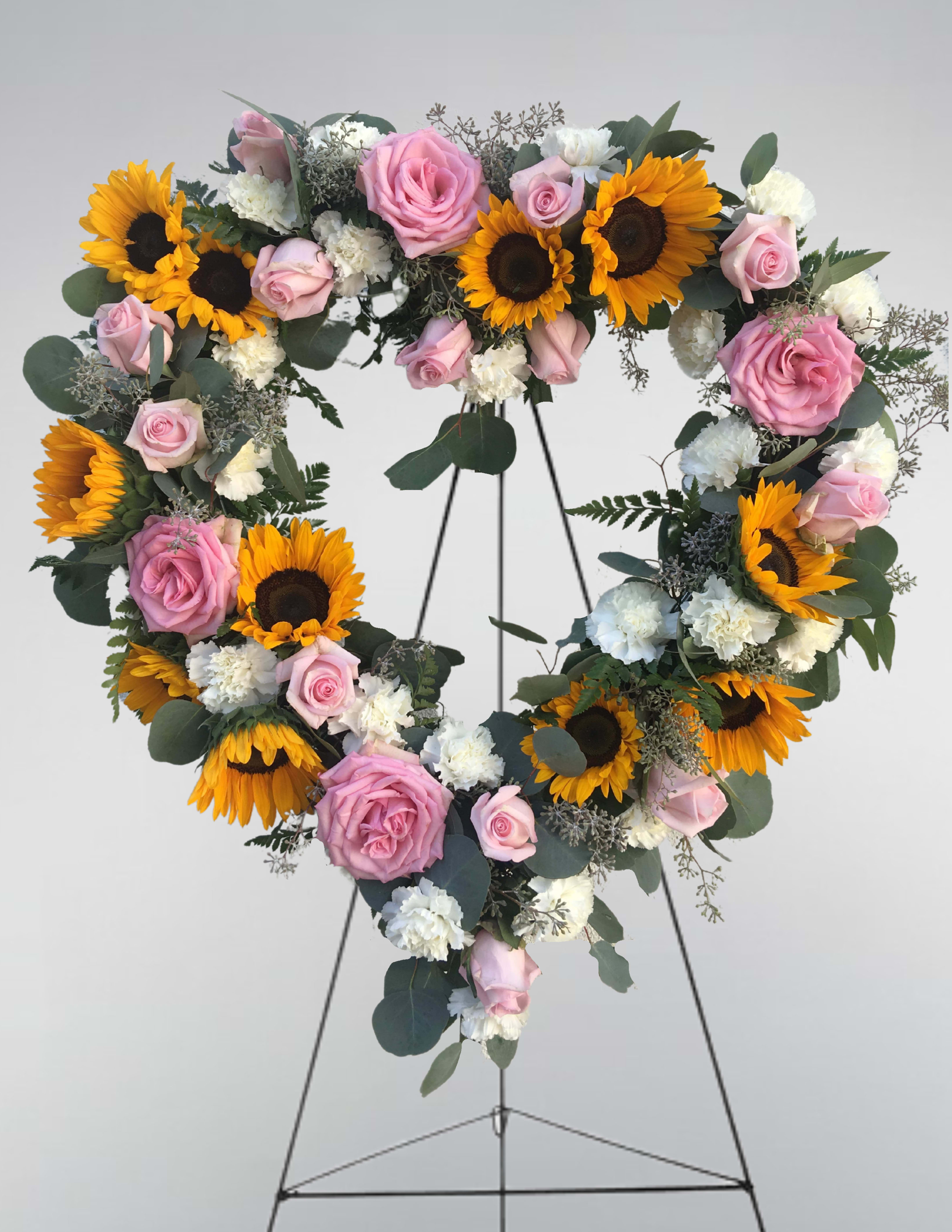 Heart-shaped floral wreath with pink roses, sunflowers, and white carnations