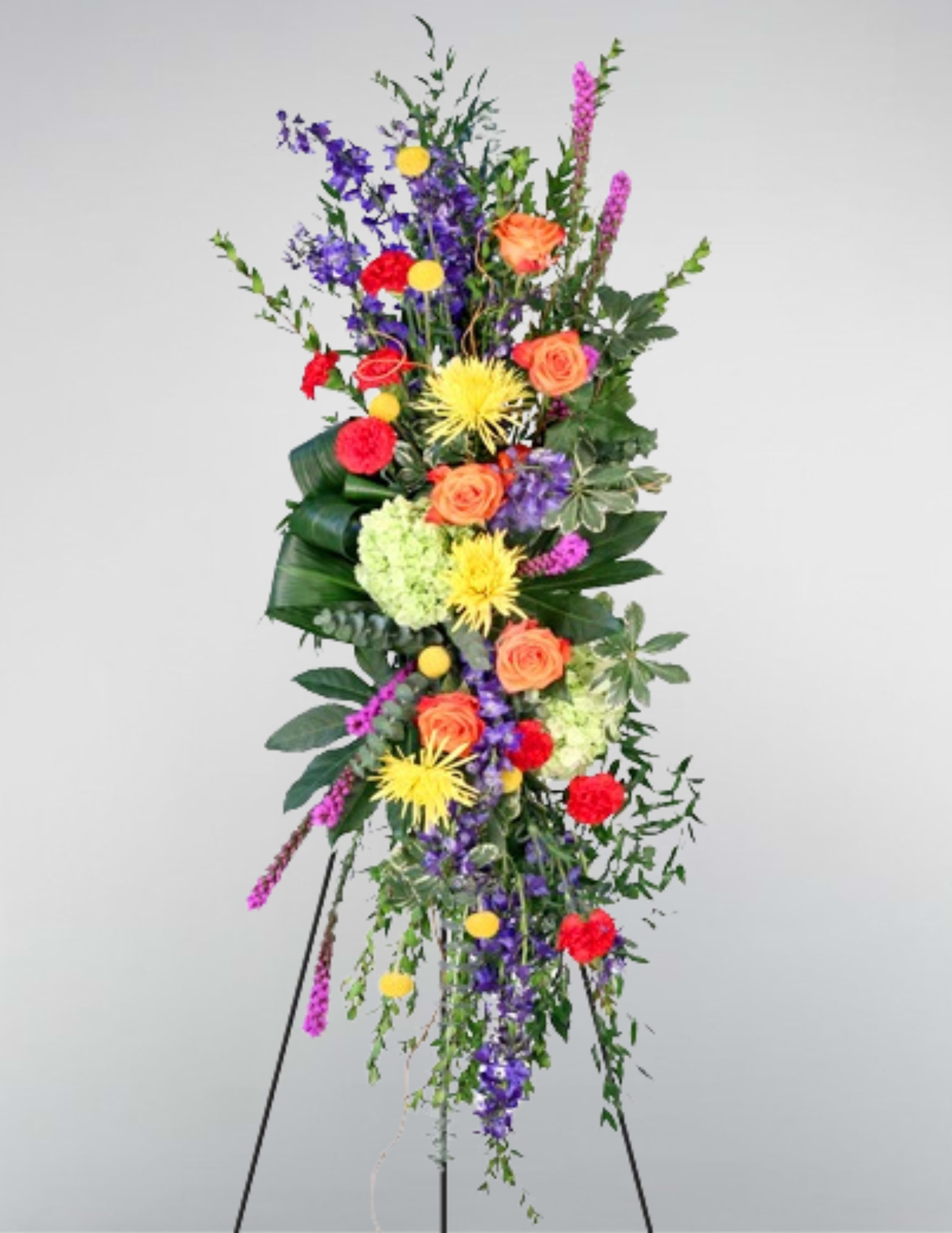 Tall standing floral spray with orange roses, purple blooms, and yellow flowers