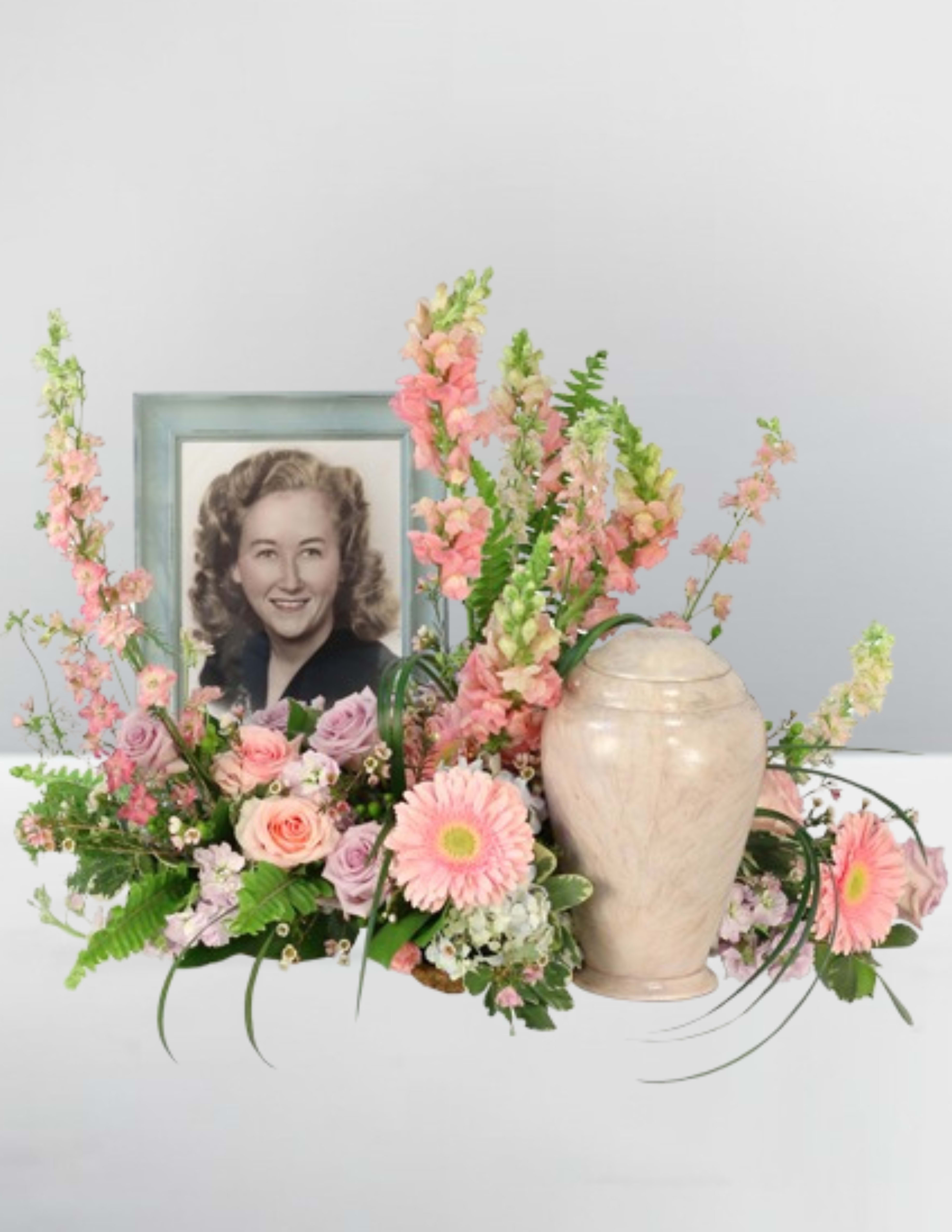 Pink floral arrangement with a framed portrait and urn
