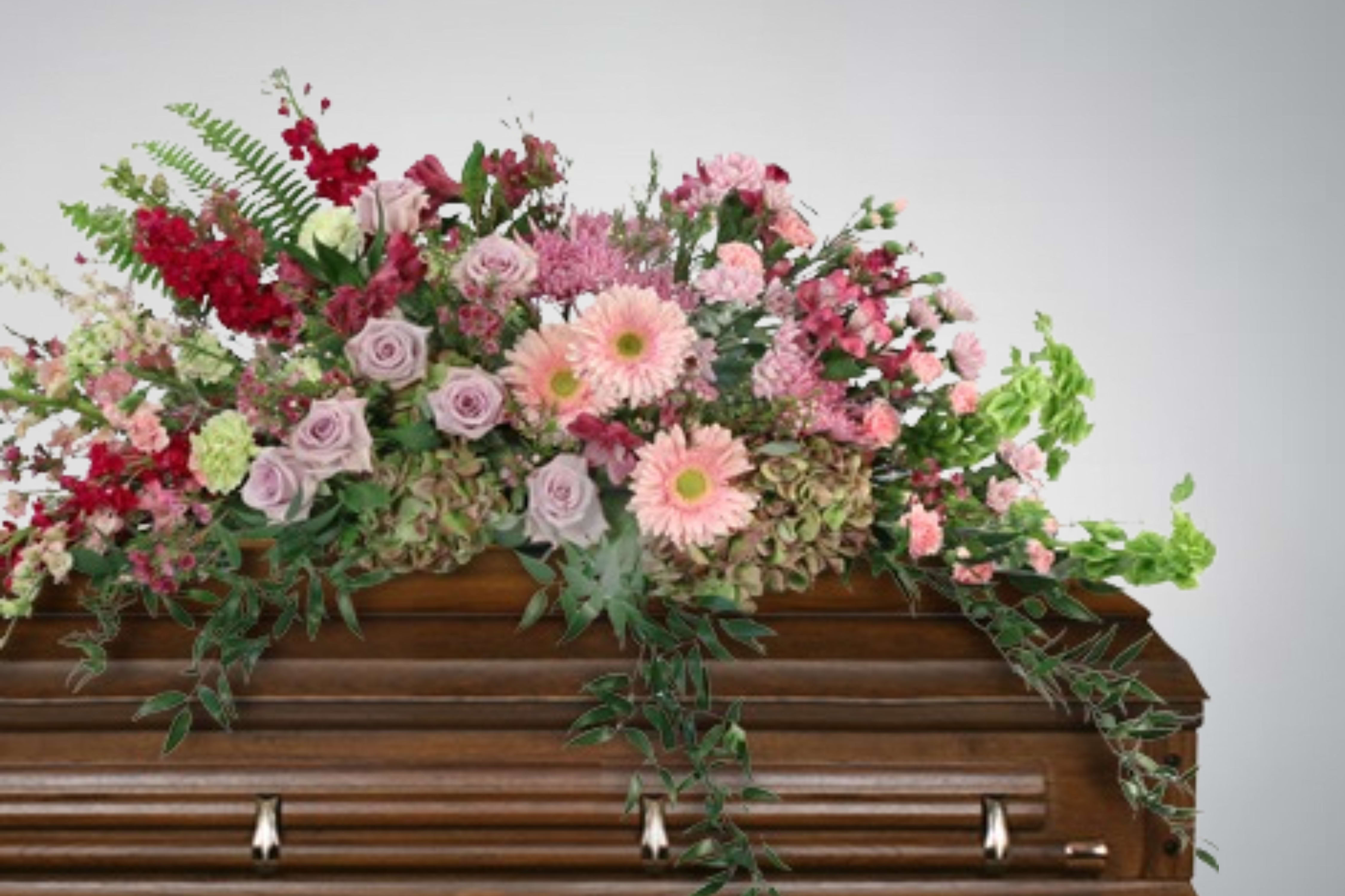 Floral spray of pink and red flowers on a wooden casket