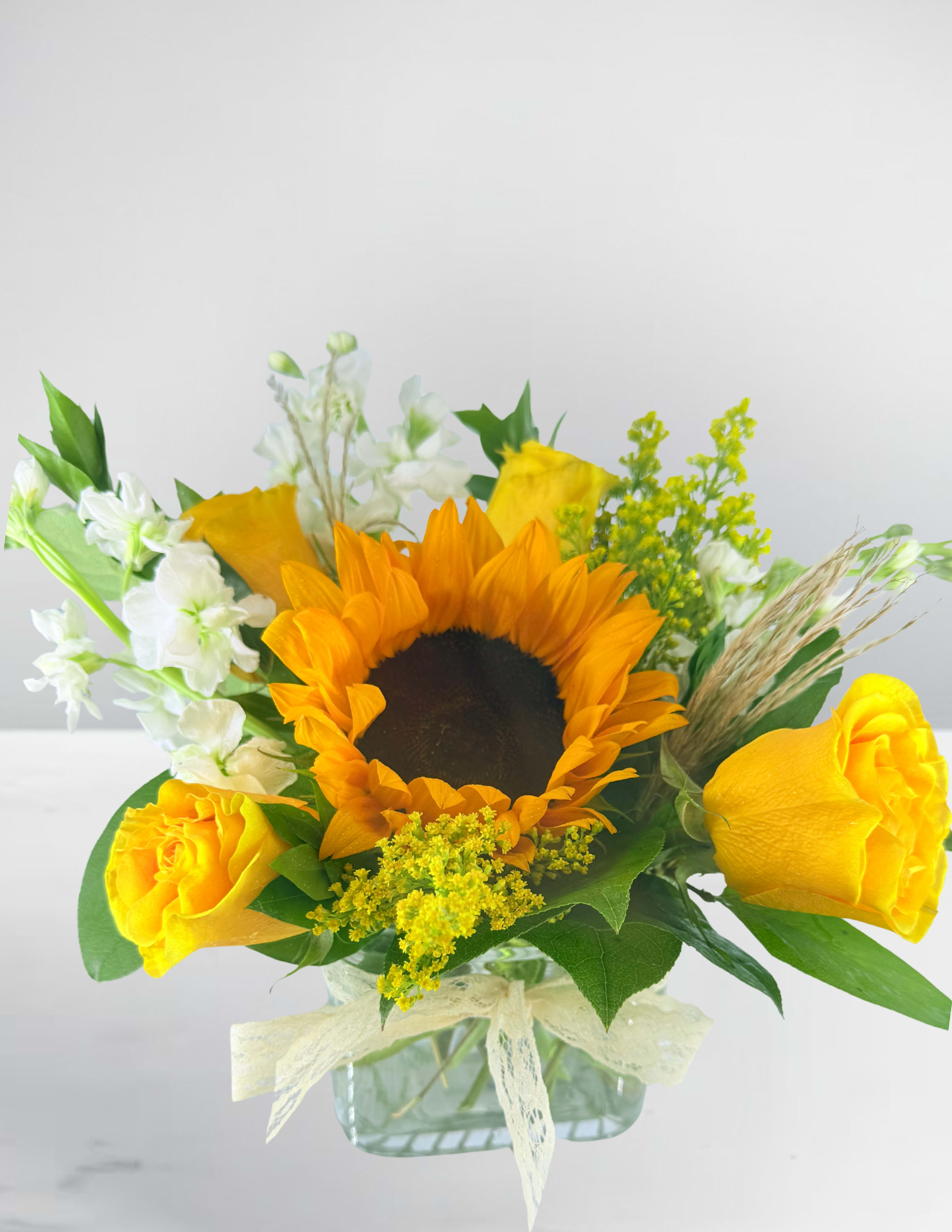 Sunflower and yellow rose bouquet in a glass vase