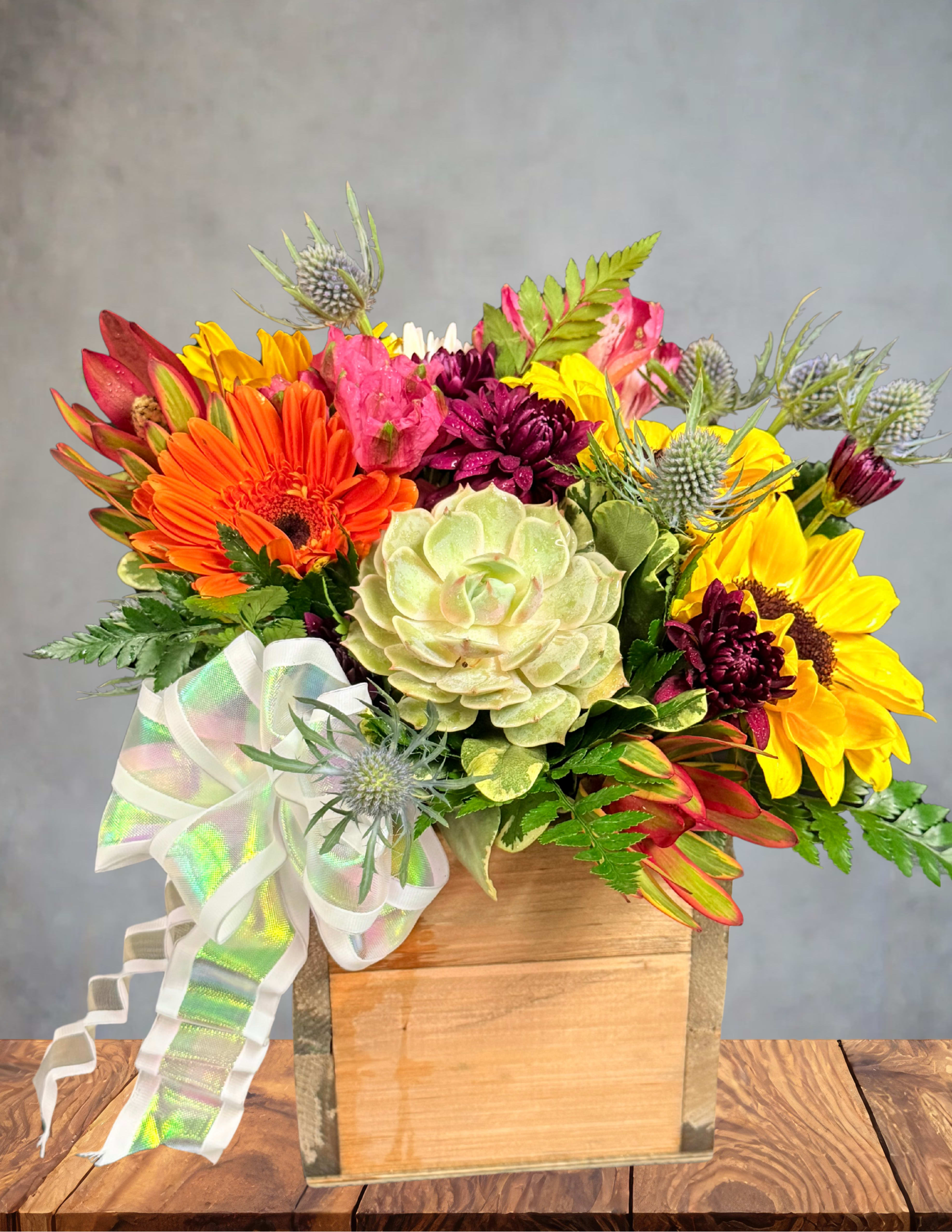 Mixed bouquet with sunflowers, gerbera daisies, and succulents in a wooden box