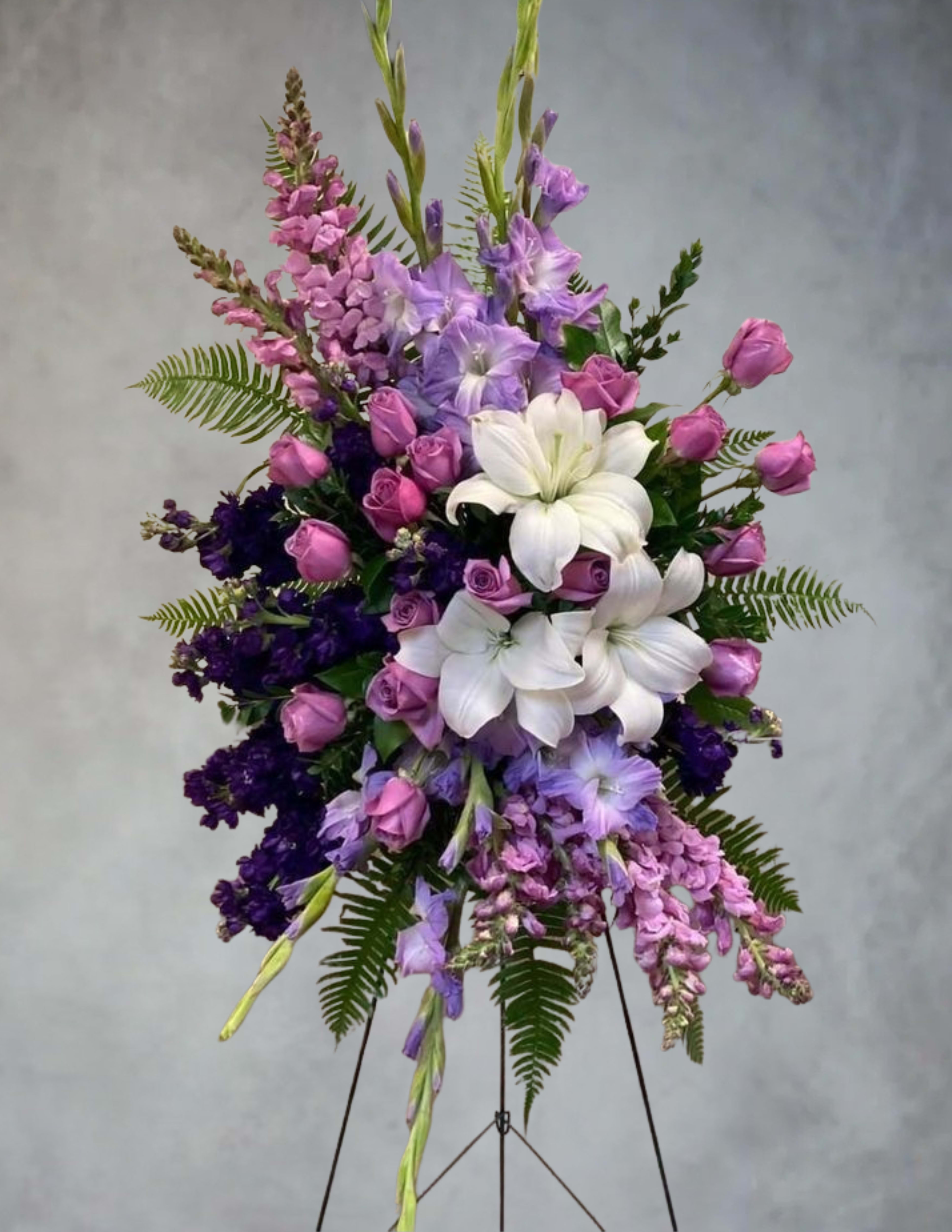 Standing floral spray with white lilies, pink roses, and purple blooms
