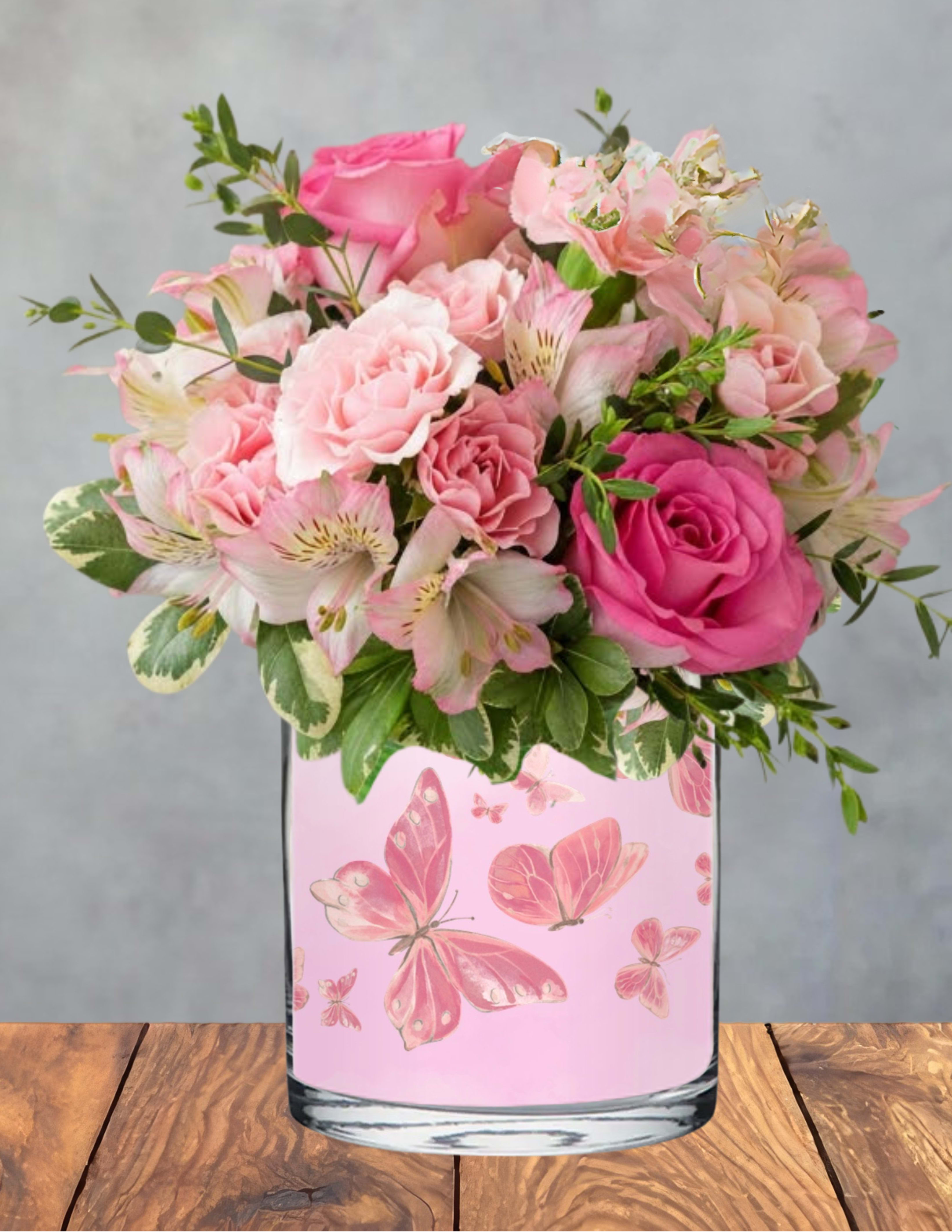 Butterfly garden  - A full cluster of pink roses in varied shades greets the eye first, a soft, feminine focal point that makes this flower arrangement perfect for a birthday bouquet, a heartfelt thank-you, or a Just Because surprise. Pale alstroemeria and ruffled carnations nestle around the roses, with small sprigs of greenery adding fresh texture and lift; the clear glass vase wrapped in a delicate pink butterfly design gives the whole piece a light, garden-fresh feel that will make the recipient feel truly seen.  Arranged for a polished gift presentation, the bouquet arrives with a gold "Happy Mother's Day" topper-ideal if you're celebrating Mother's Day or Women's Day, but the styling fits equally well for Best Friends Day or everyday appreciation. The vase and stems create a compact, display-ready piece that sits well on a table or desk; gentle daily water changes and trimming an inch from stems every few days will keep blooms looking their best.