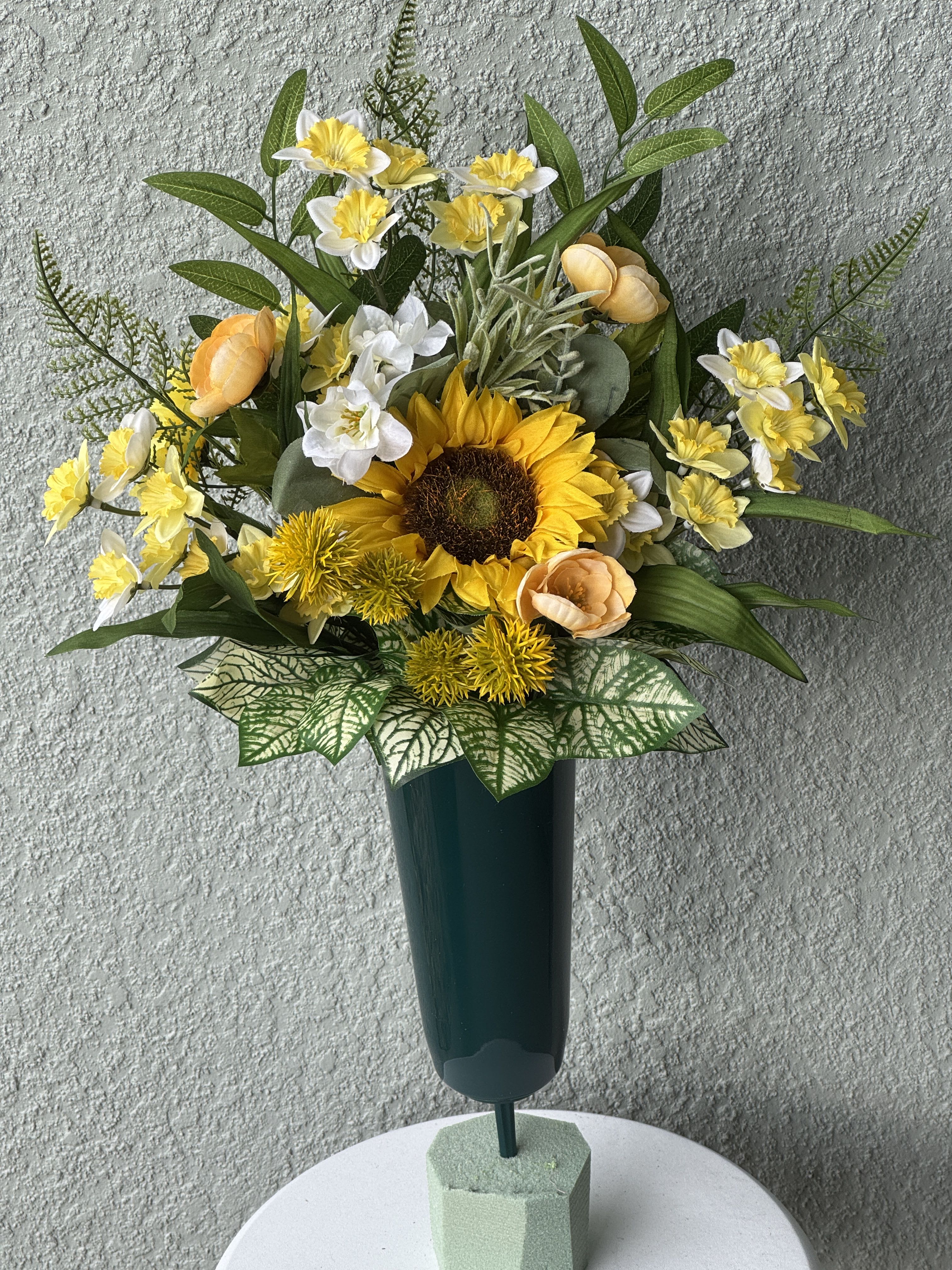 Yellow and white floral arrangement in a tall dark vase