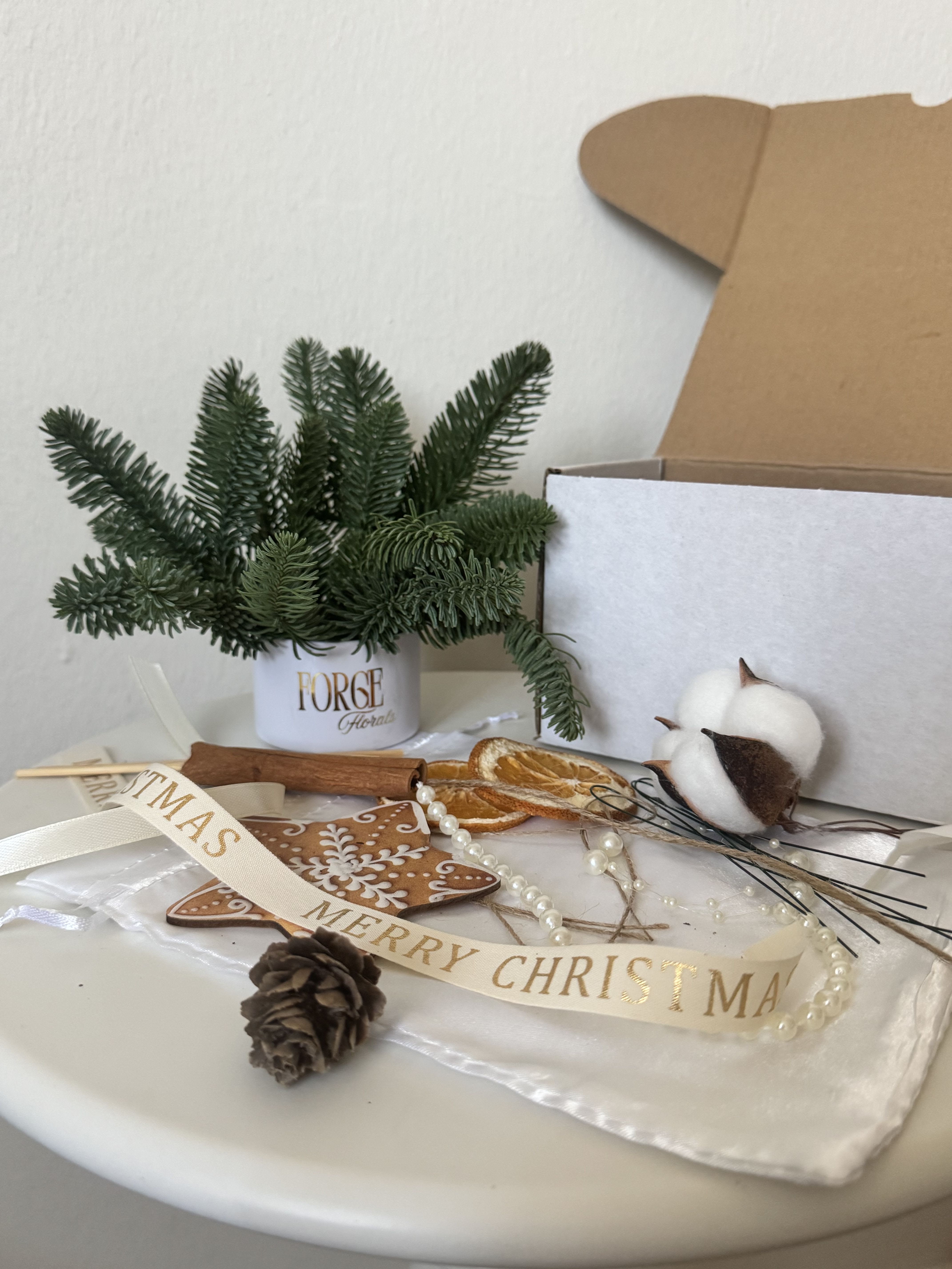 DIY Centerpiece  - Bring cozy holiday vibes home — in just 5–10 minutes. This DIY kit includes a mini arrangement of premium Nobilis fir set in water-holding floral foam, plus festive décor so you can build your own mini centerpiece (or gift it to someone who loves crafting).  Nobilis fir is known for its soft, full look and long-lasting freshness — it holds its shape beautifully and stays tidy with minimal shedding.  What’s included 	•	Mini tin with fresh Nobilis fir set in floral foam 	•	Dried orange slices + pinecone 	•	Ribbon + mini décor pieces 	•	4 pieces of floral wire to attach ornaments and bows 	•	Easy instructions (hot glue gun optional)  Make it your way  Cut orange slices for a custom look, trim the ribbon, and add your own ornaments from home — every kit can look totally different.  Care  Add a small splash of water to the foam every couple of days to keep the fir fresh. Keep away from radiators/heaters and direct heat.  Perfect for: small tables, desk décor, hostess gifts, and last-minute holiday presents.