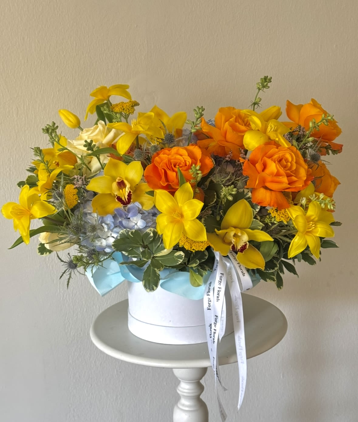 Sunshine Escape-Orchids, roses, hydrangeas,tulips(will be replaced when not in season) - A vibrant and joyful design bursting with golden orchids, sunny tulips, bright orange roses, soft blue hydrangea, and whimsical seasonal blooms. Inspired by warm summer days and tropical gardens, this arrangement brings energy, happiness, and a touch of luxury to any space.