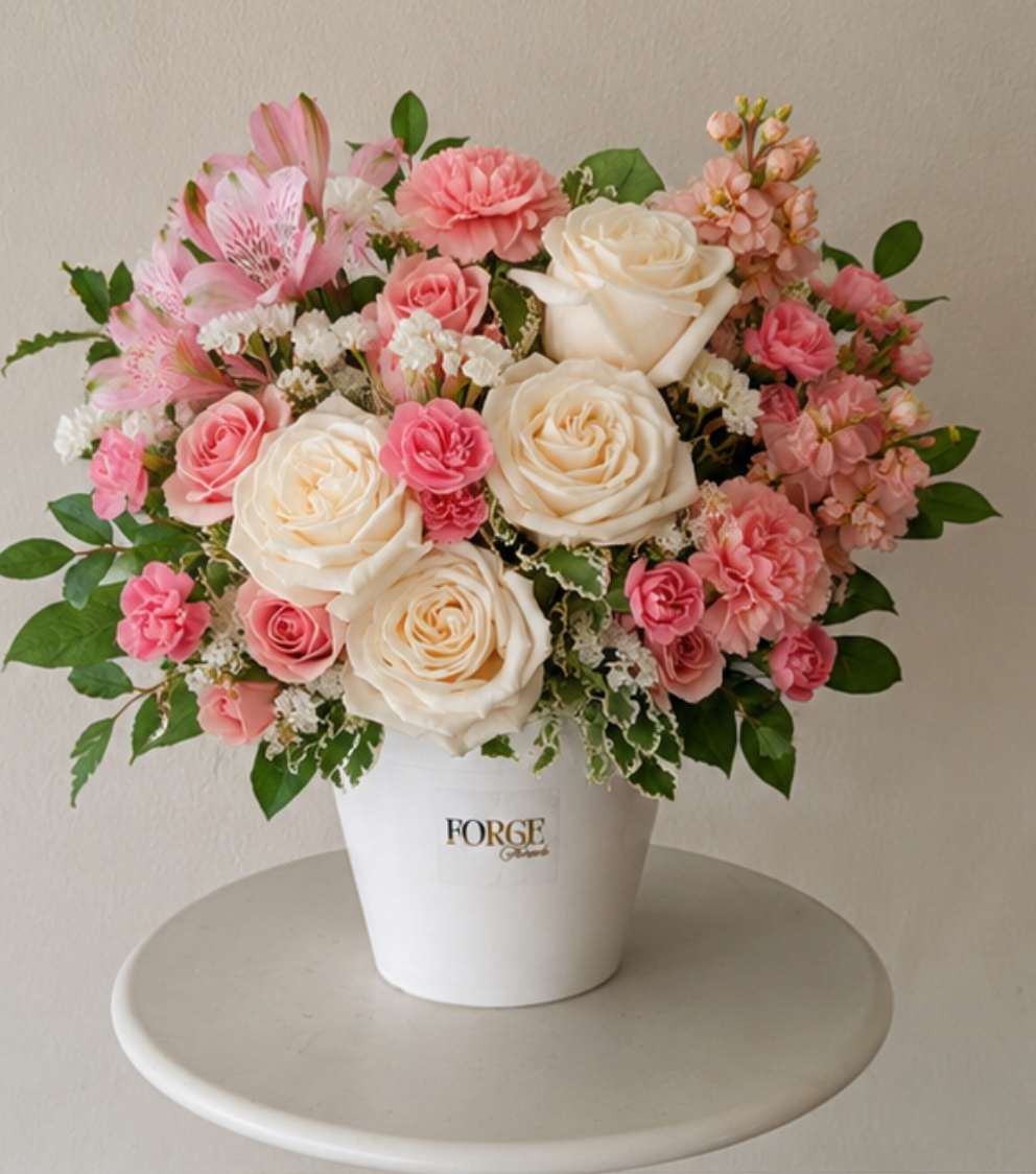 Pink and cream flower arrangement in a white pot