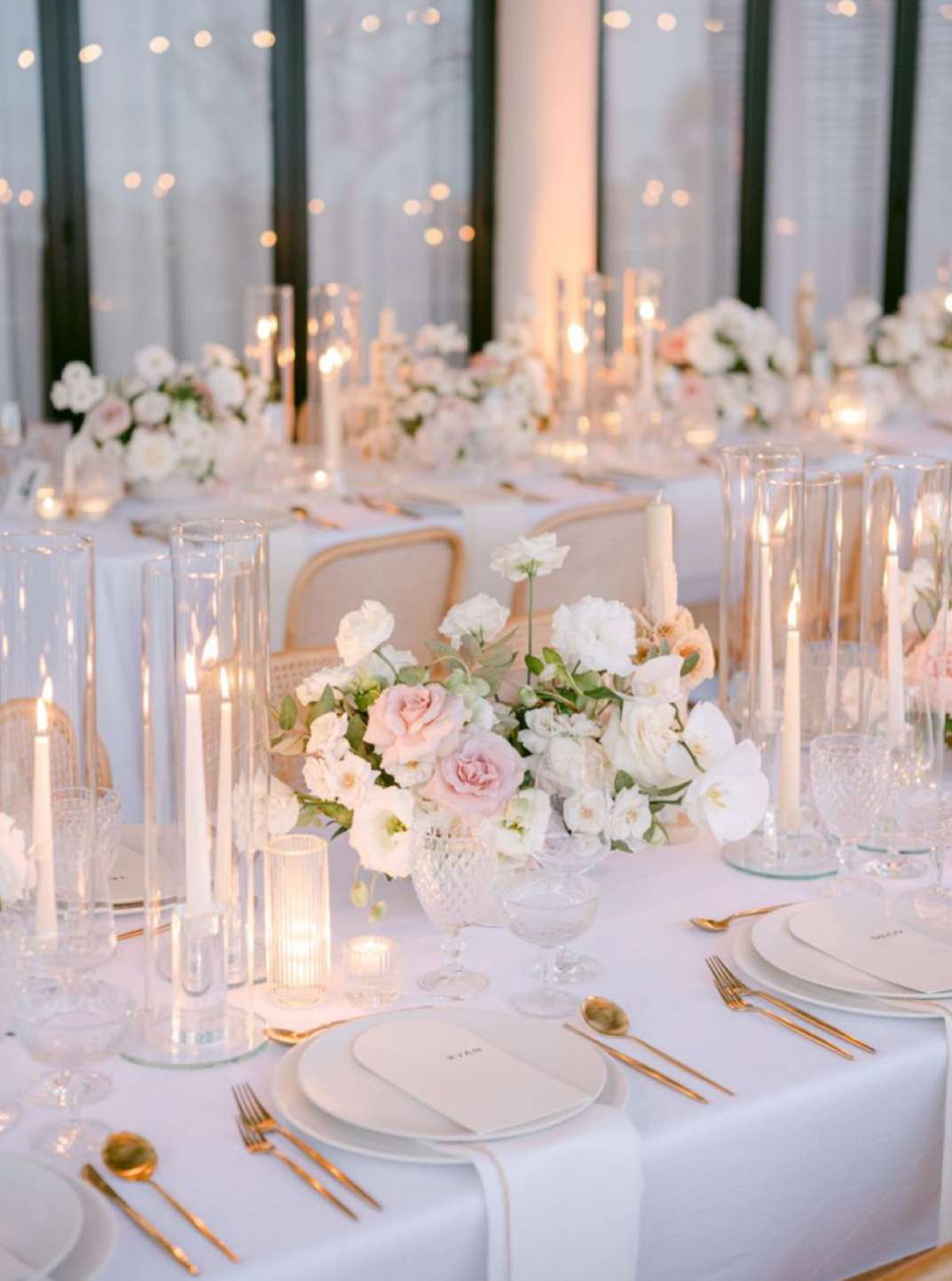 White and blush floral centerpieces on a candlelit banquet table
