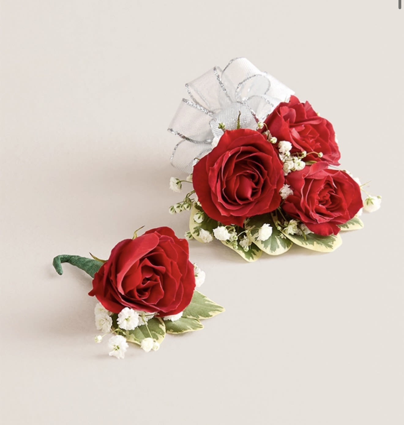 Red Corsage &amp; Boutonniere Set (Silver Bow) - This elegant corsage and boutonniere set, featuring vibrant red blooms, is thoughtfully designed to pair perfectly, creating a polished and harmonious look for any special occasion. Each piece showcases carefully selected red flowers and accents, offering a timeless and refined touch that complements your ensemble beautifully.