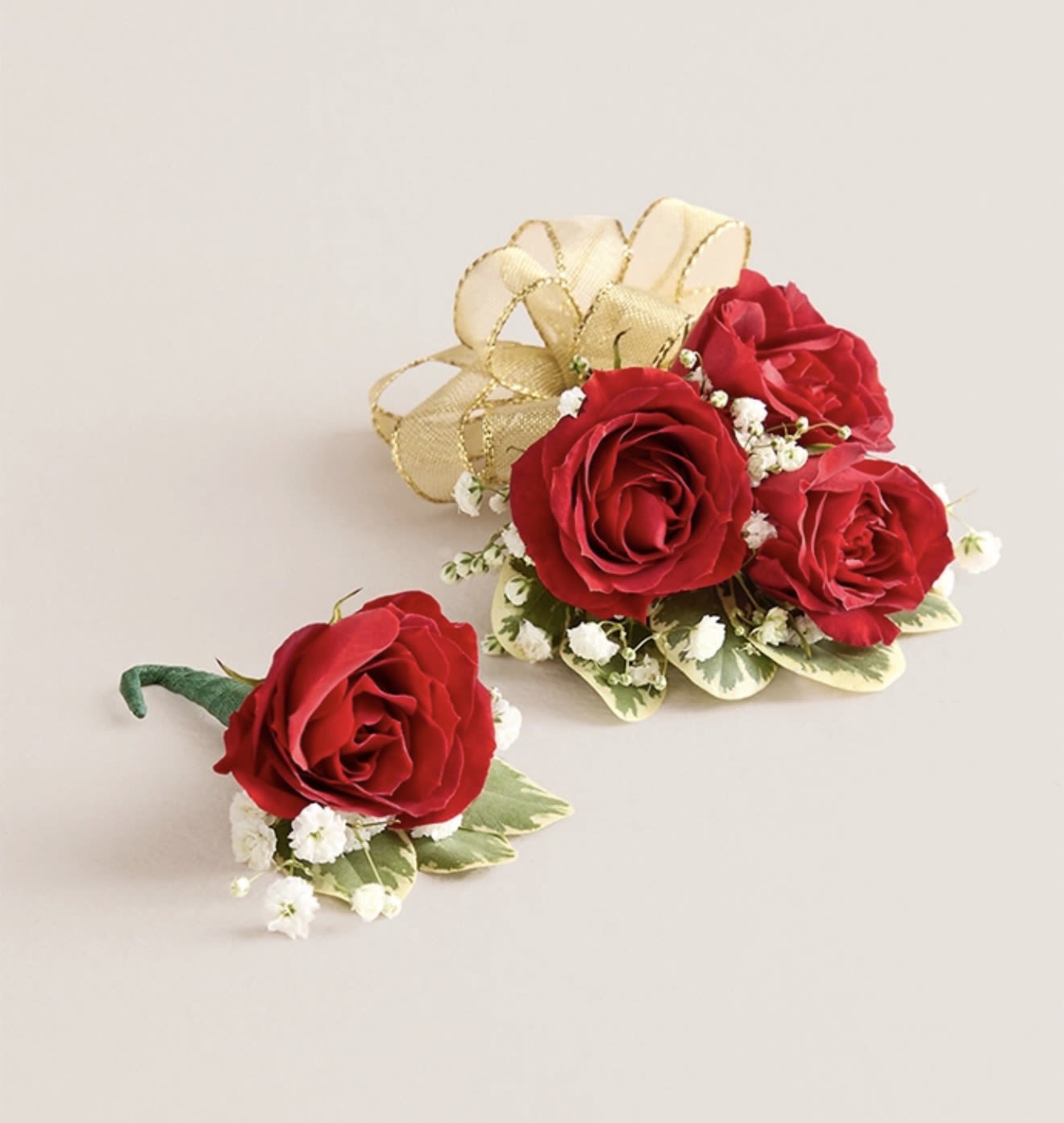 Red Corsage &amp; Boutonniere (Gold Bow) - This elegant corsage and boutonniere set, featuring vibrant red blooms, is thoughtfully designed to pair perfectly, creating a polished and harmonious look for any special occasion. Each piece showcases carefully selected red flowers and accents, offering a timeless and refined touch that complements your ensemble beautifully.