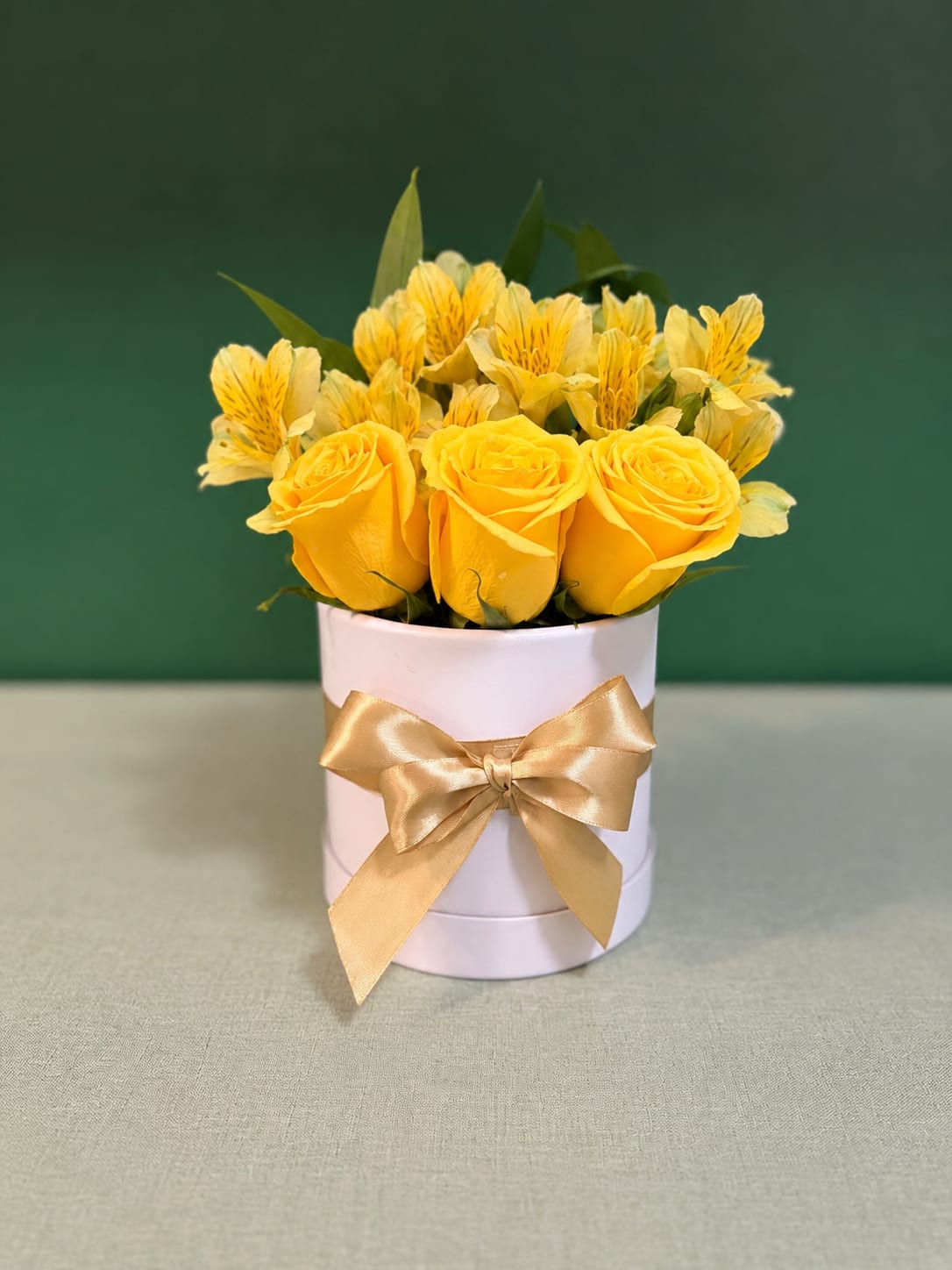 Yellow roses and yellow alstroemeria in a white round box with a gold ribbon
