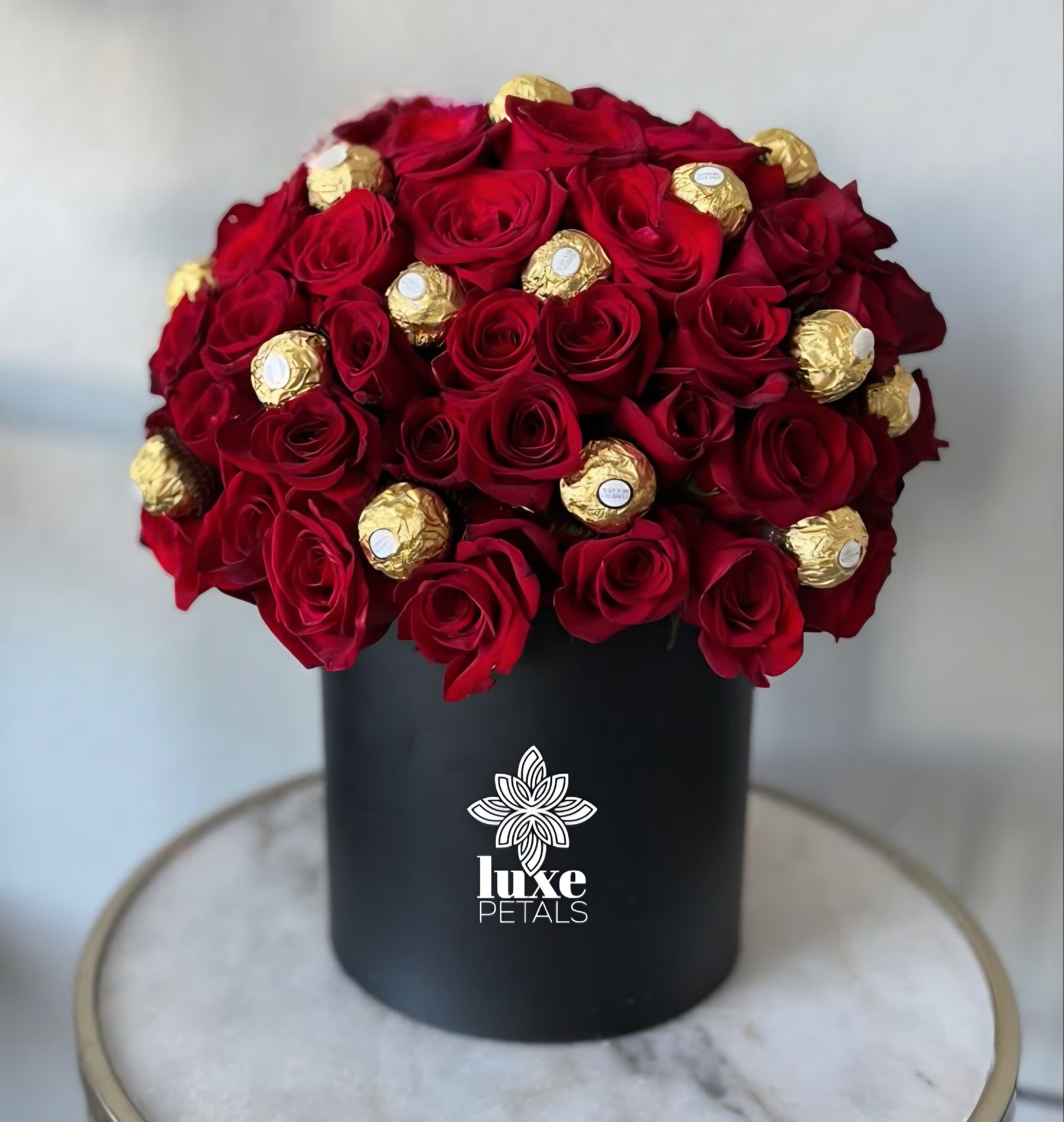 Red roses and gold-wrapped chocolates in a black box