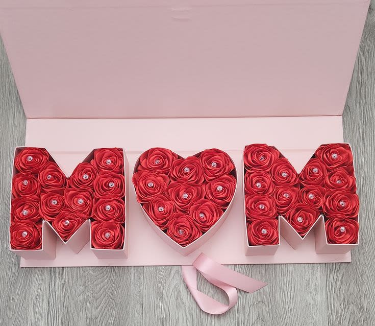 Heart-shaped rose box between two letter boxes with a pink ribbon