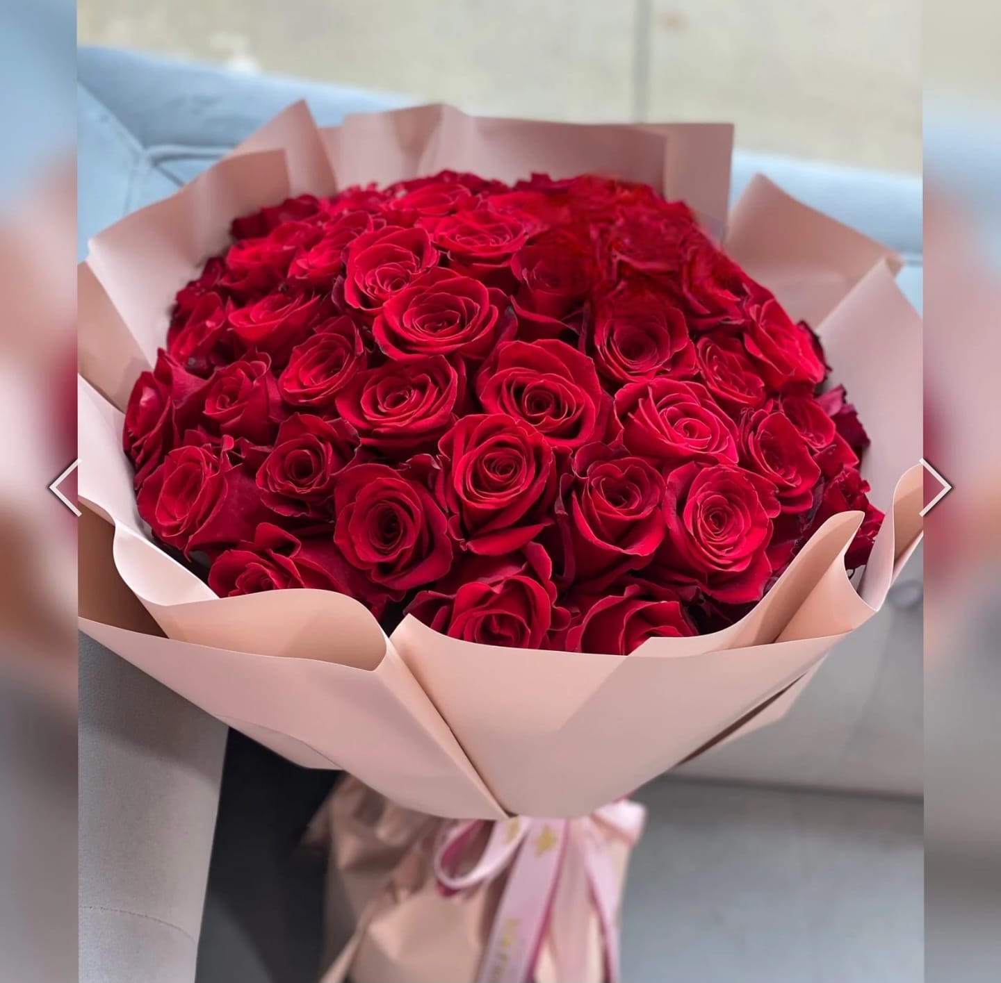 Large bouquet of red roses wrapped in pale pink paper