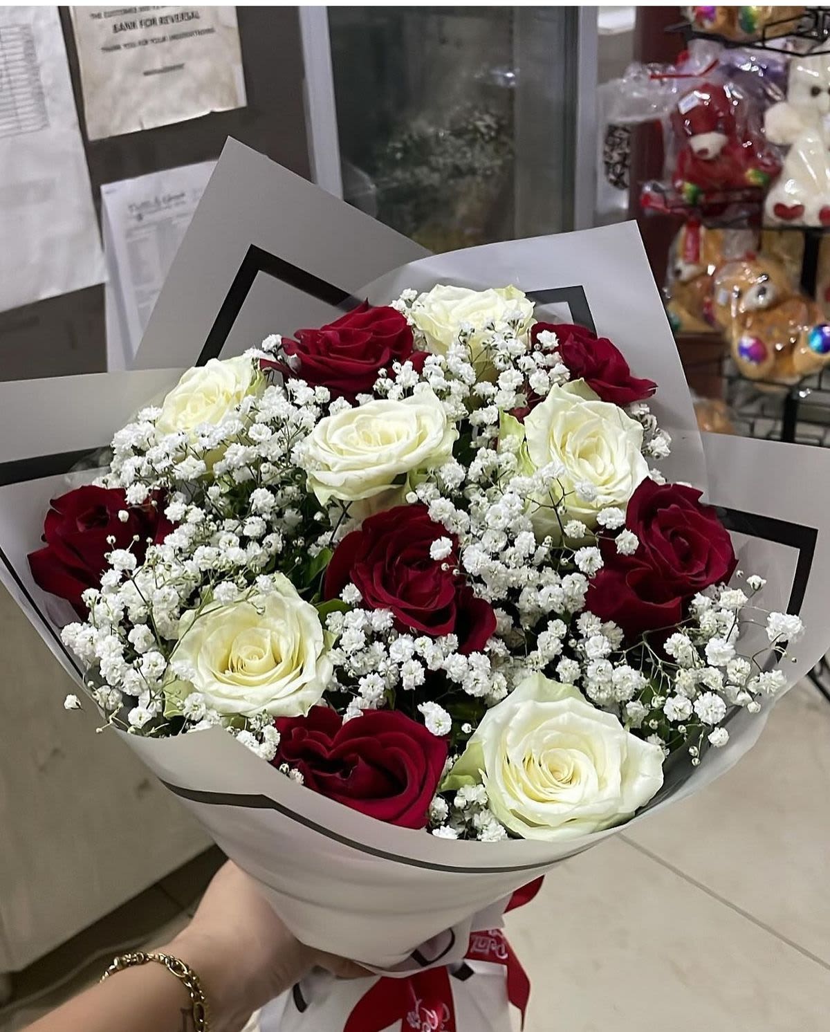 Eternal loved - Deep red and creamy white roses are artfully combined in this Eternal Mom flower arrangement for Mother's Day, anniversary, or a heartfelt everyday surprise. The rounded, hand-tied silhouette reads classic and romantic-the kind of bouquet that makes the person you're thinking of feel cherished the moment it arrives.  The bouquet features deep red roses, pale creamy roses, and clusters of small white filler flowers for soft texture and fullness. Wrapped in crisp white floral paper and finished with a ribbon at the base, it arrives gift-ready with a polished, formal presentation and a balanced, full shape that photographs beautifully.  Perfect for mothers, partners, or anyone who treasures timeless elegance, this arrangement sends a message of deep affection and appreciation. Order with standard sizing; hand-tied construction helps the stems stay secure-trim stems and refresh water on arrival to keep the roses looking their best.