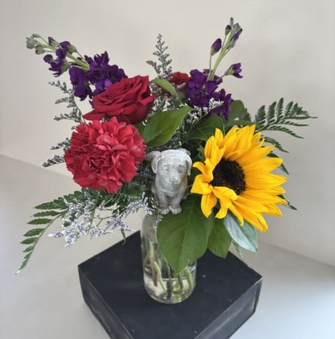 Pawprints in Heaven – Dog - Pawprints in Heaven – Dog is a heartfelt tribute created to honor the unconditional love and cherished memories of a beloved canine companion. Designed with pet-safe flowers including cheerful sunflowers, fragrant stock, classic roses, and carnations, this thoughtful arrangement offers comfort during a difficult time.  Accented with a touching dog angel pick, this meaningful tribute serves as a gentle reminder that while our faithful friends may be gone, the pawprints they leave on our hearts remain forever. A beautiful way to express sympathy and celebrate a lifetime of loyalty, love, and companionship.