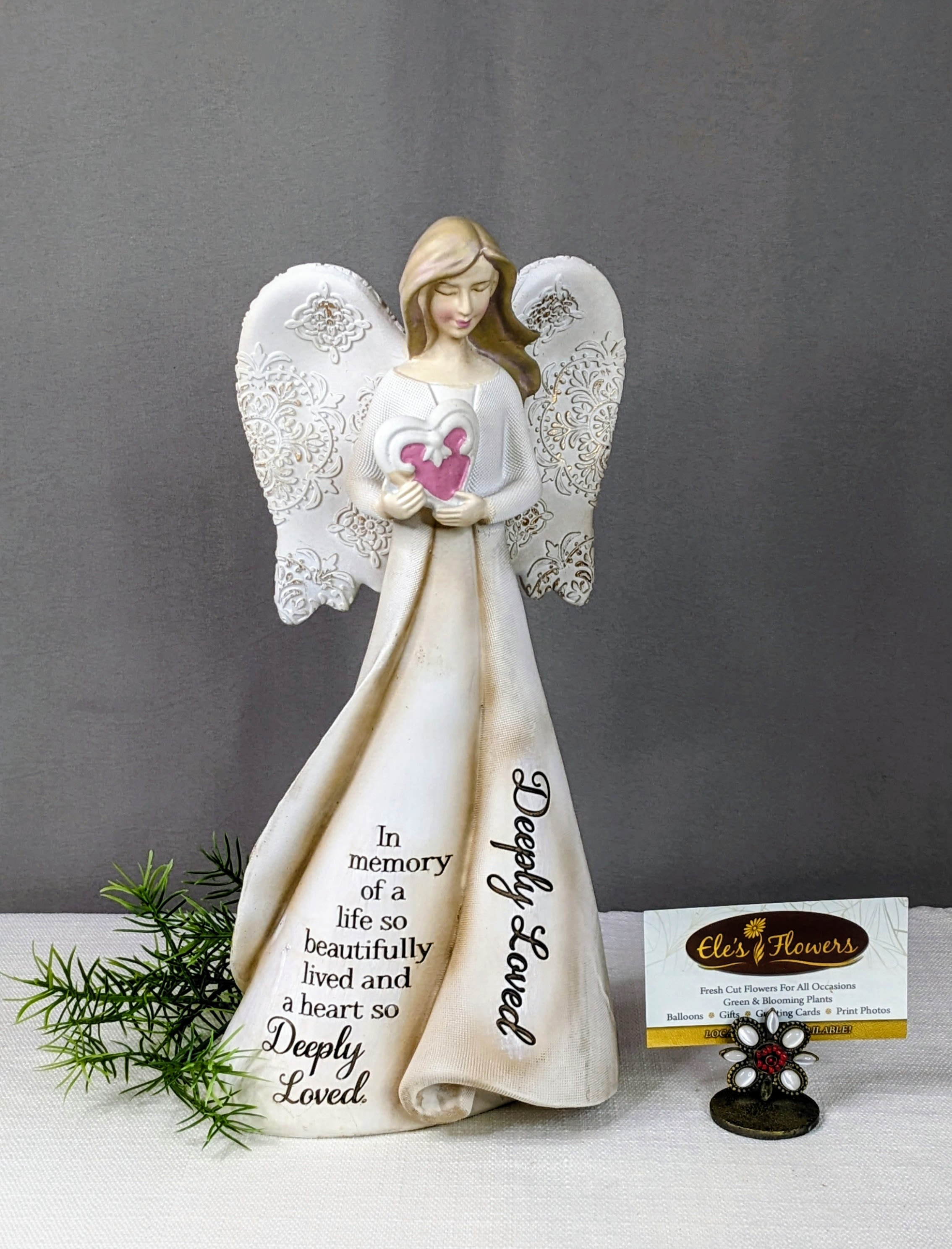 Angel figurine holding a heart with a memorial message on her dress