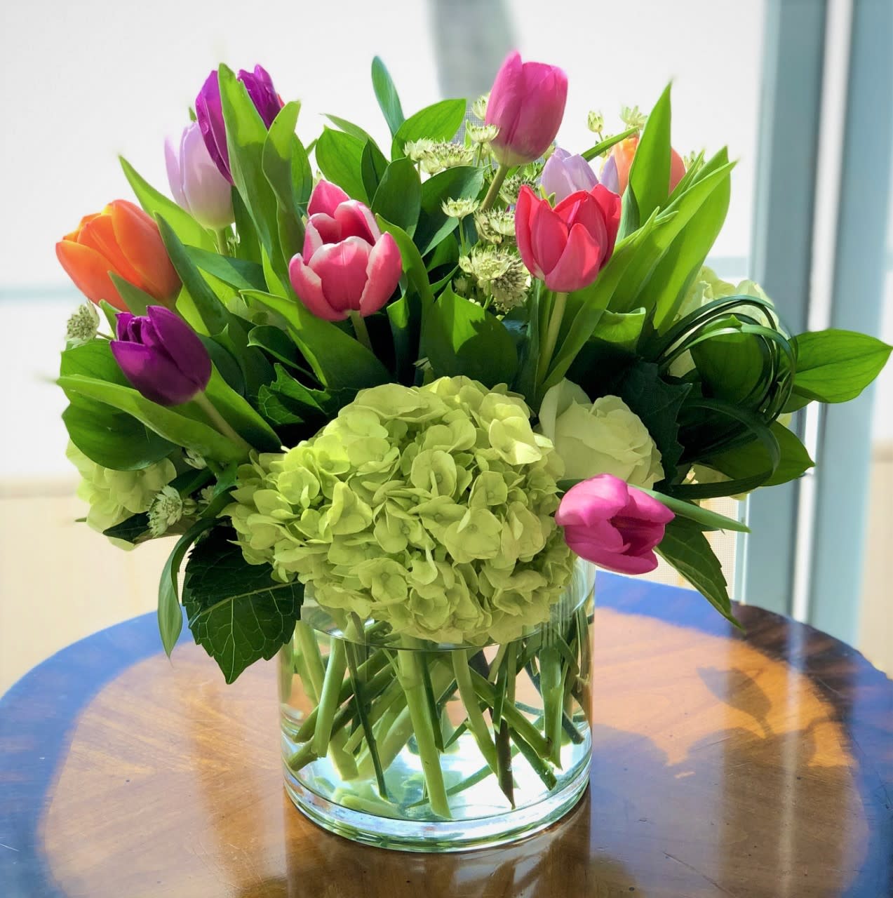 Spring Preppy Combo - Nothing says Spring like Tulips. Mixed with a combination of assorted blossoms in a clear glass vase. Looking for a happy flowers? This is it.